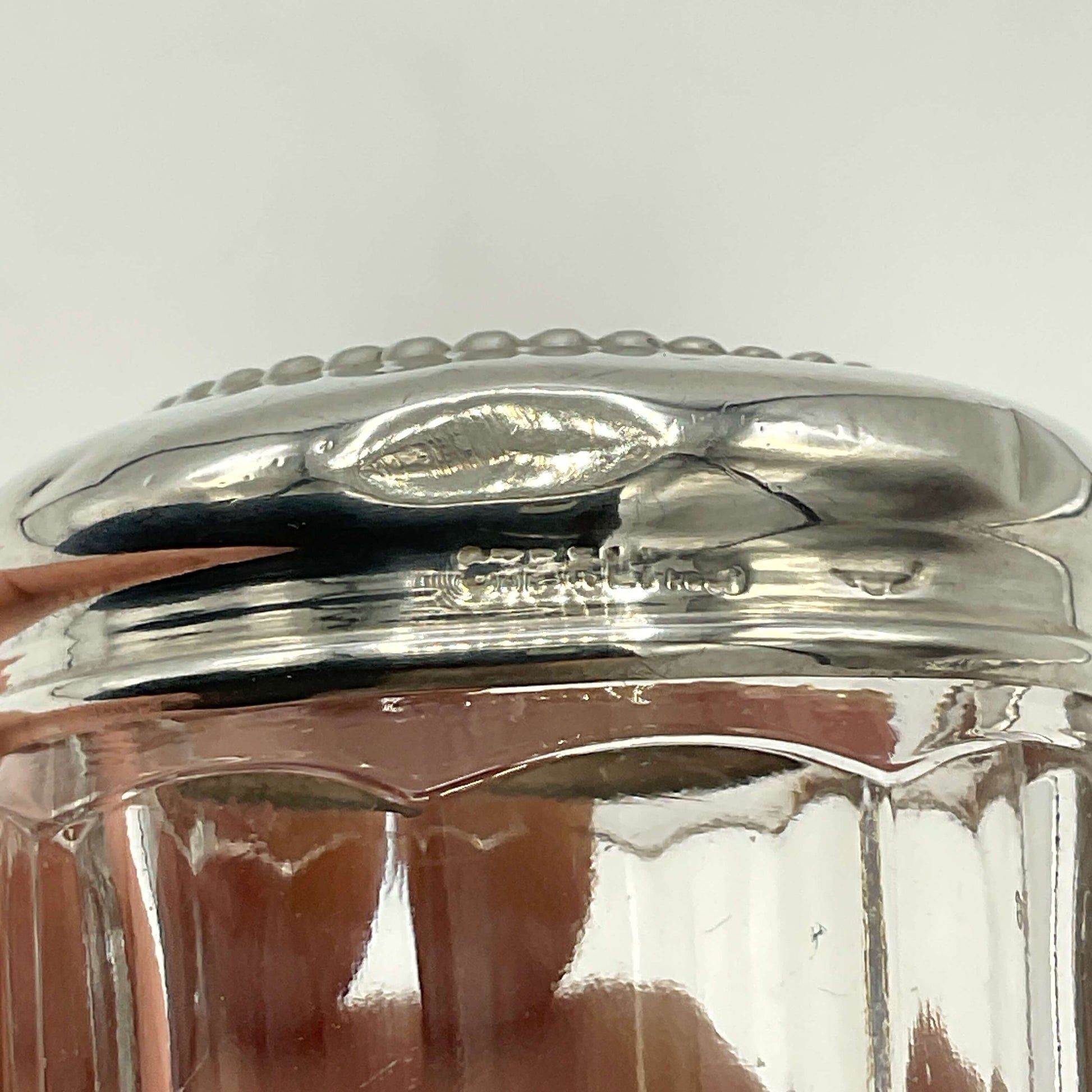 Close-up of a silver lid on a glass jar with a white background