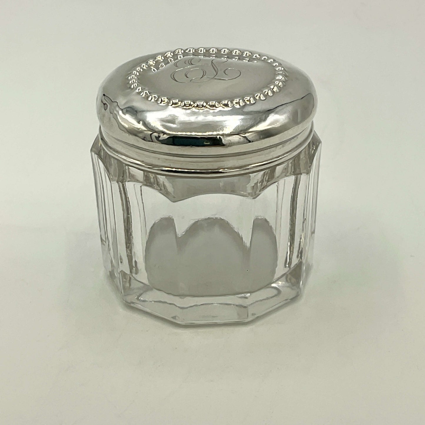Clear glass jar with a silver lid on a white background