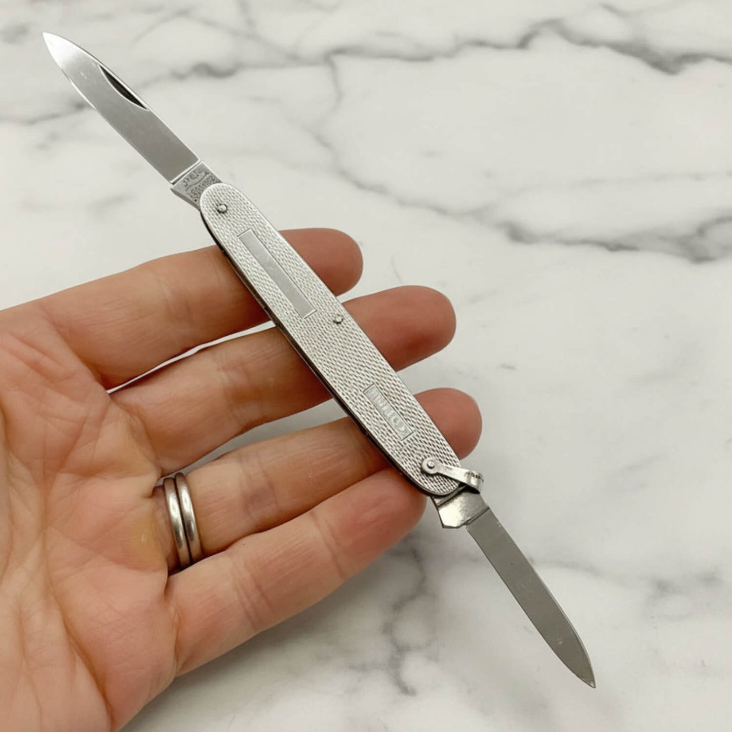 Vintage Sterling Silver Pen Knife held in a hand with a marble background
