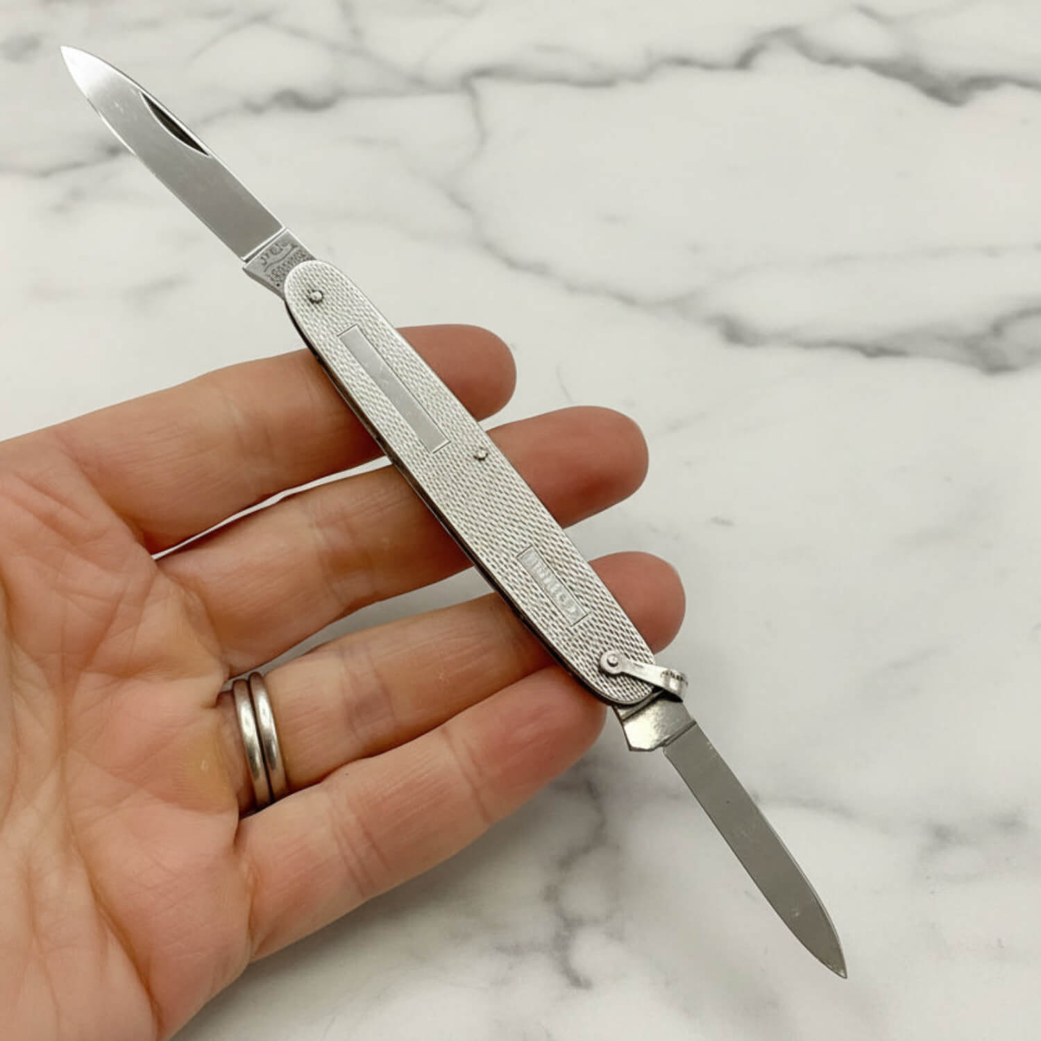Vintage Sterling Silver Pen Knife held in a hand with a marble background