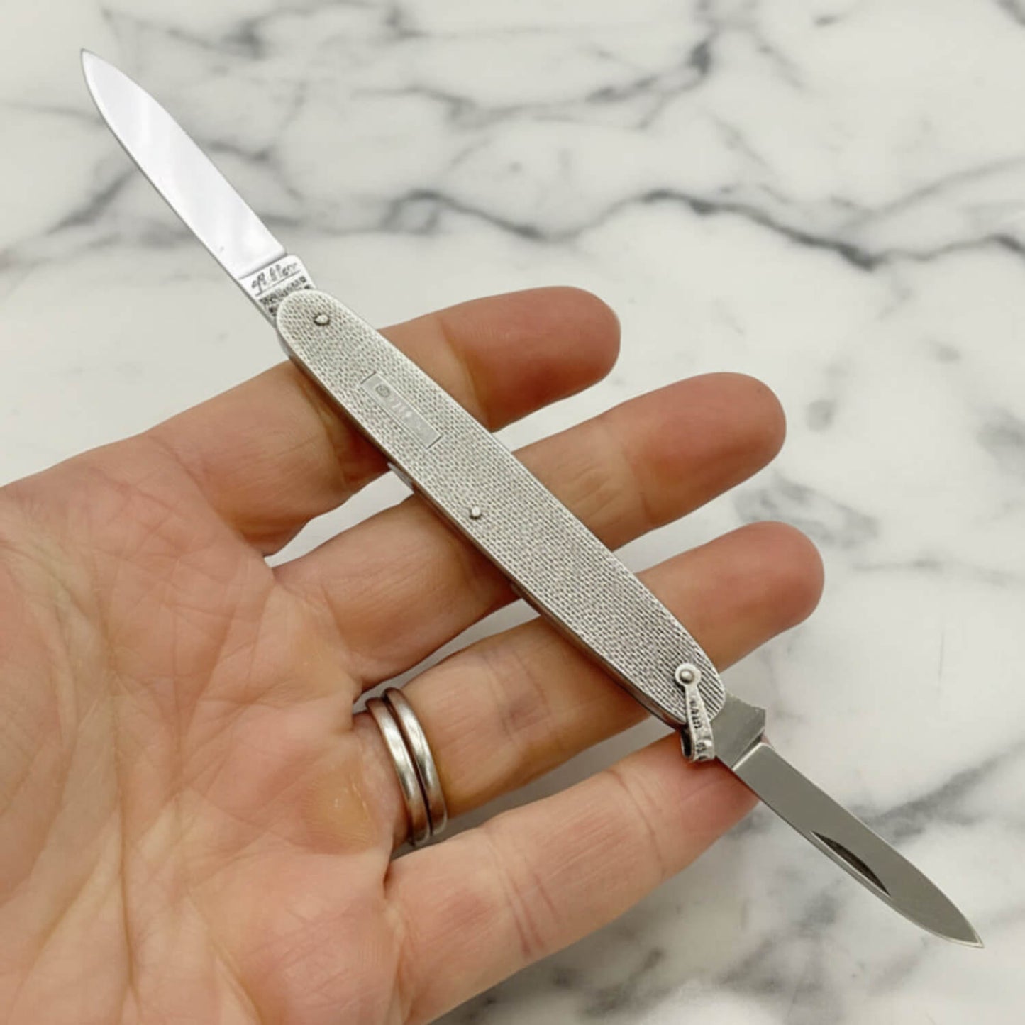 Vintage Sterling Silver Pen Knife in a hand with a marble background