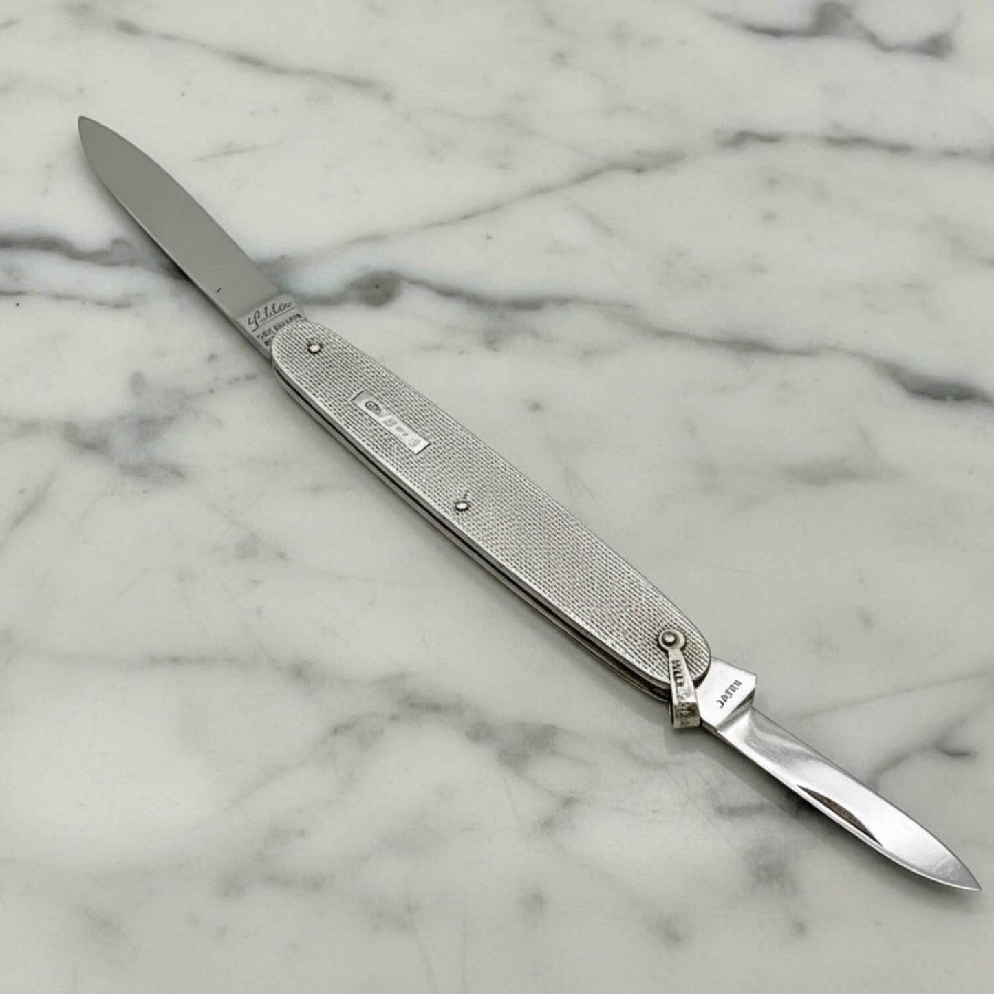 Silver pen knife with engraved details on a marble surface