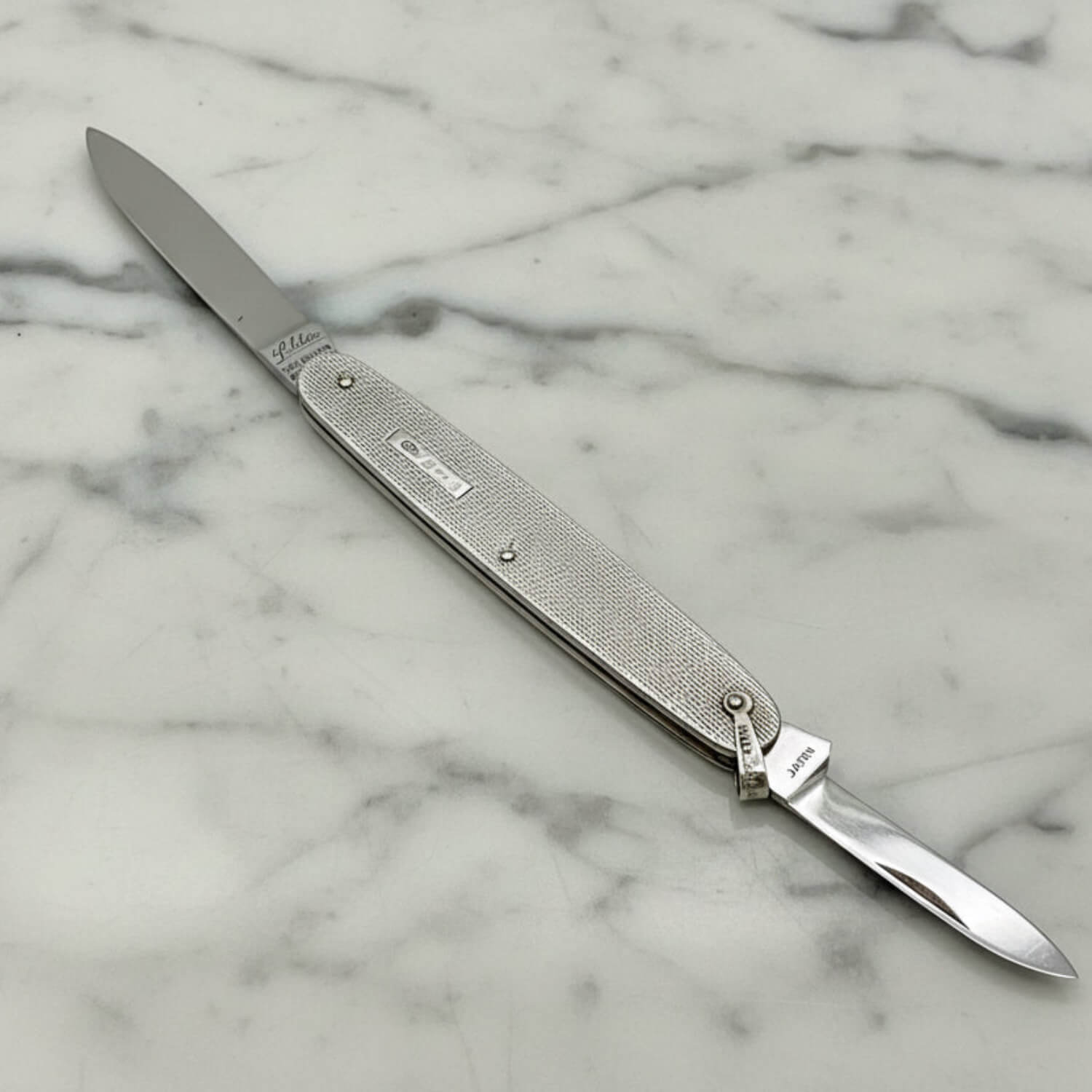 Silver pen knife with engraved details on a marble surface