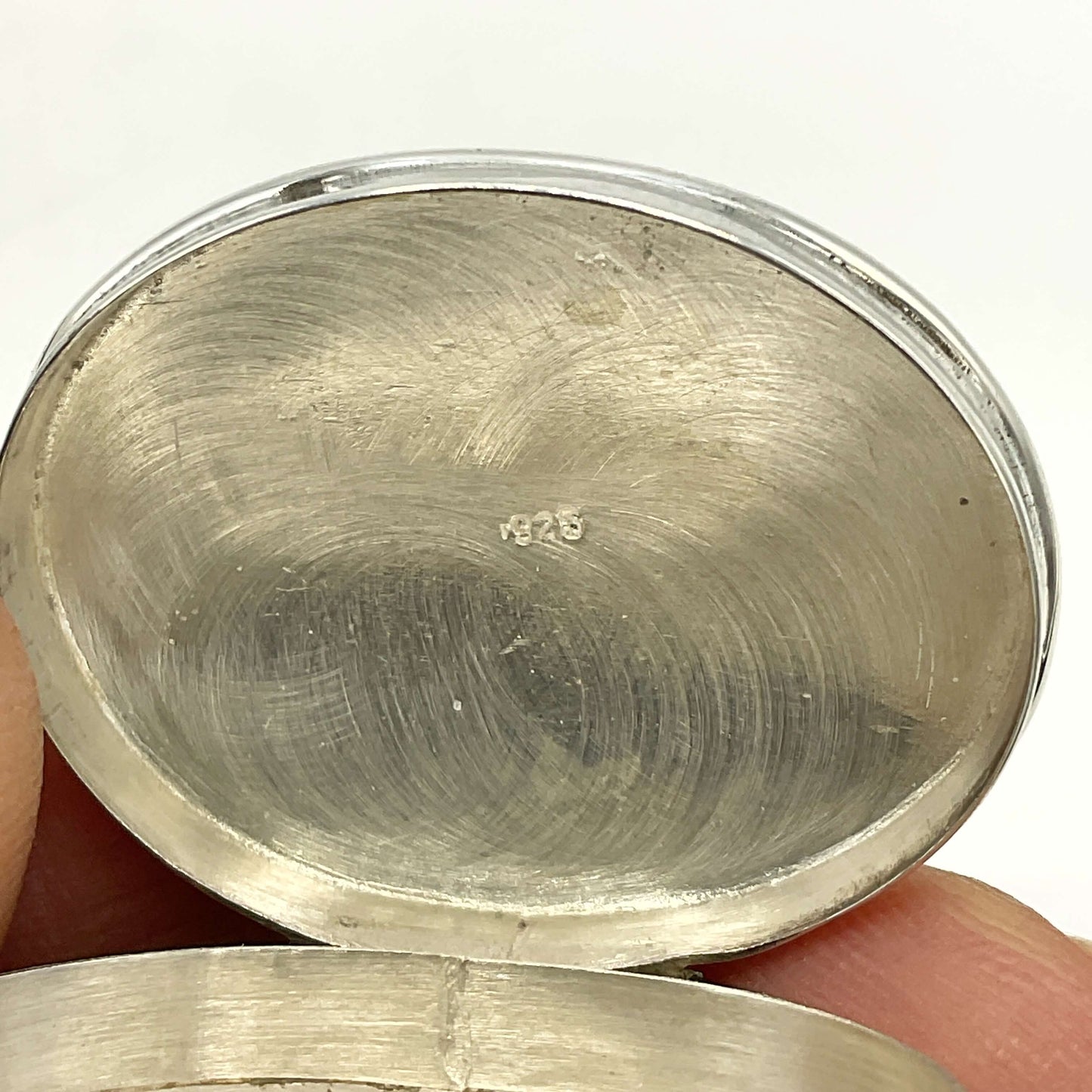 Vintage Sterling Silver Pill Box lid inside showing 925 held in fingers with a white background
