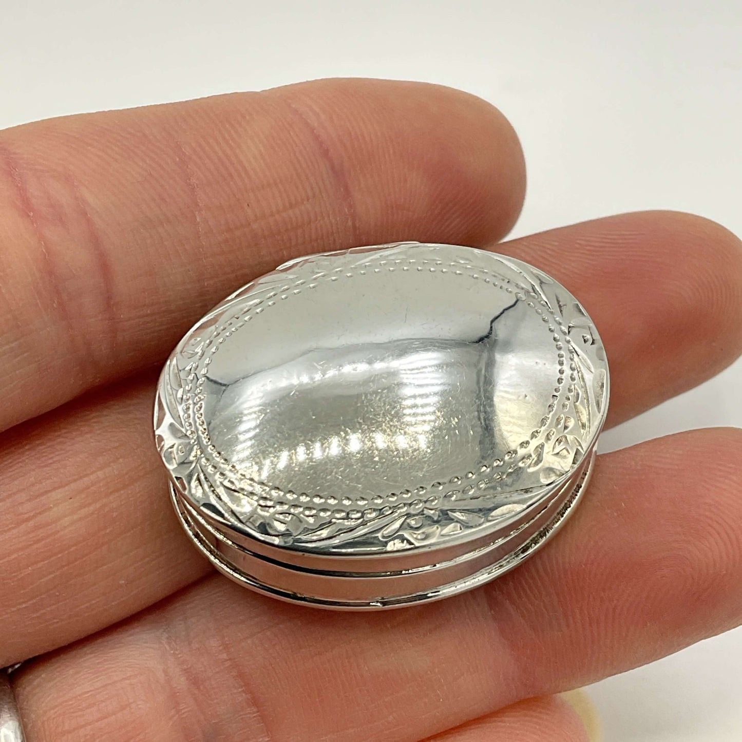 Vintage Sterling Silver Pill Box held in a hand with a white background