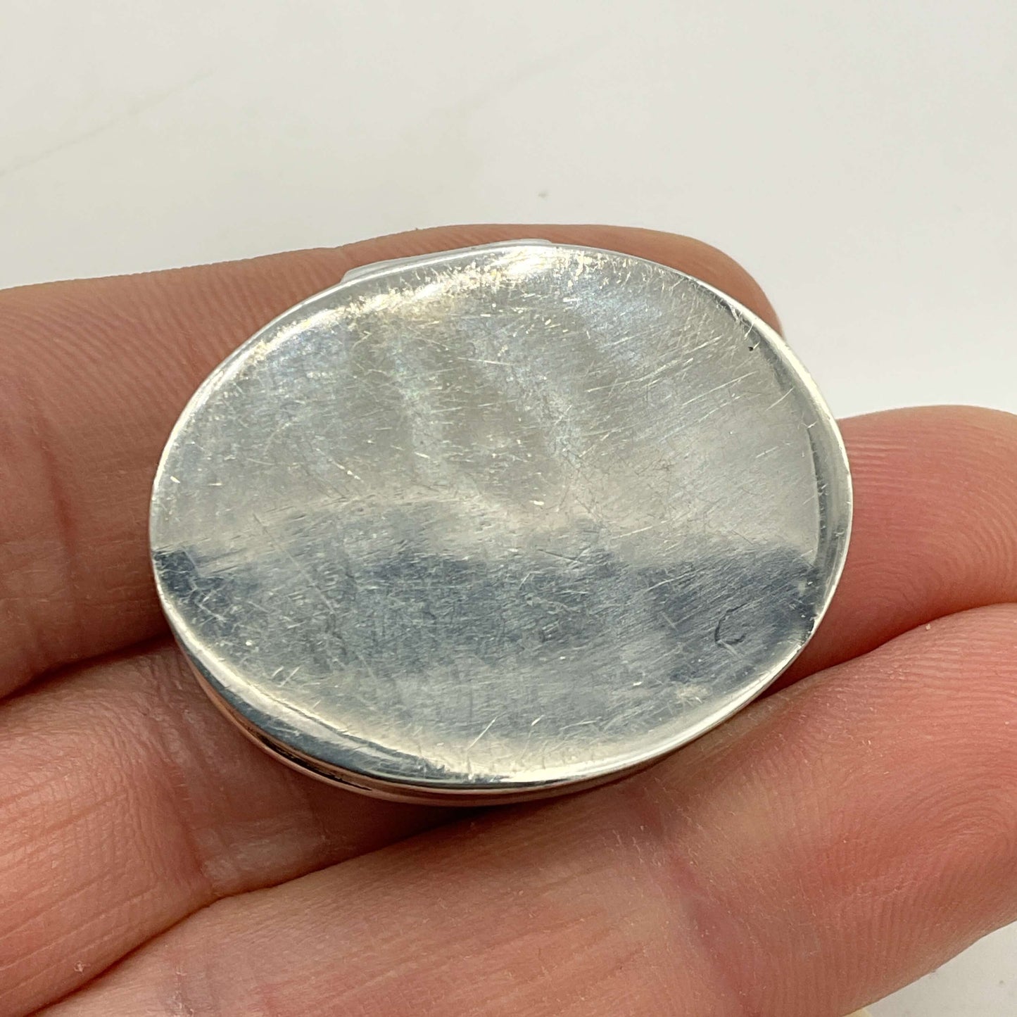 Base of Vintage Sterling Silver Pill Box held in hand with a white background