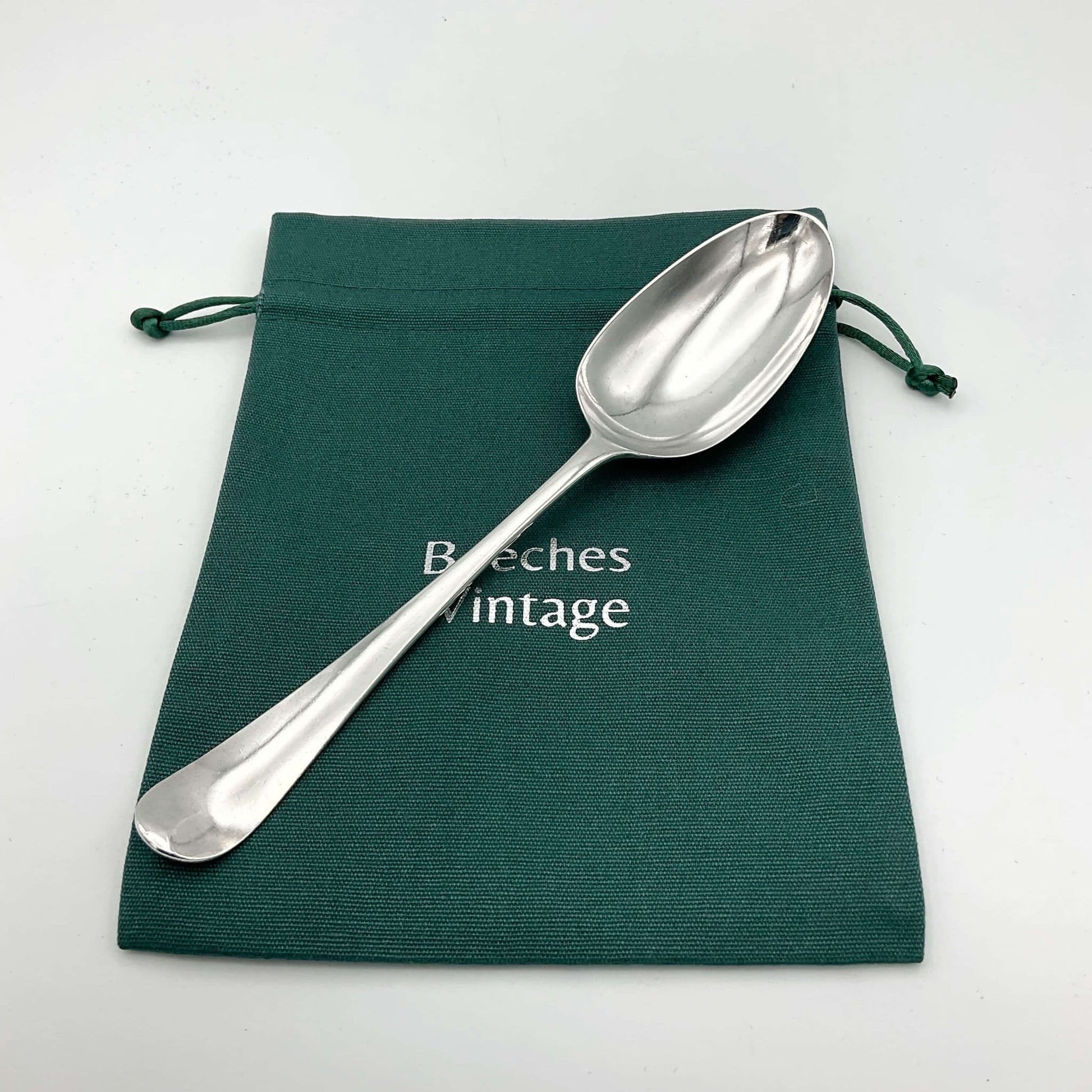 Antique silver serving spoon on a green cotton bag 