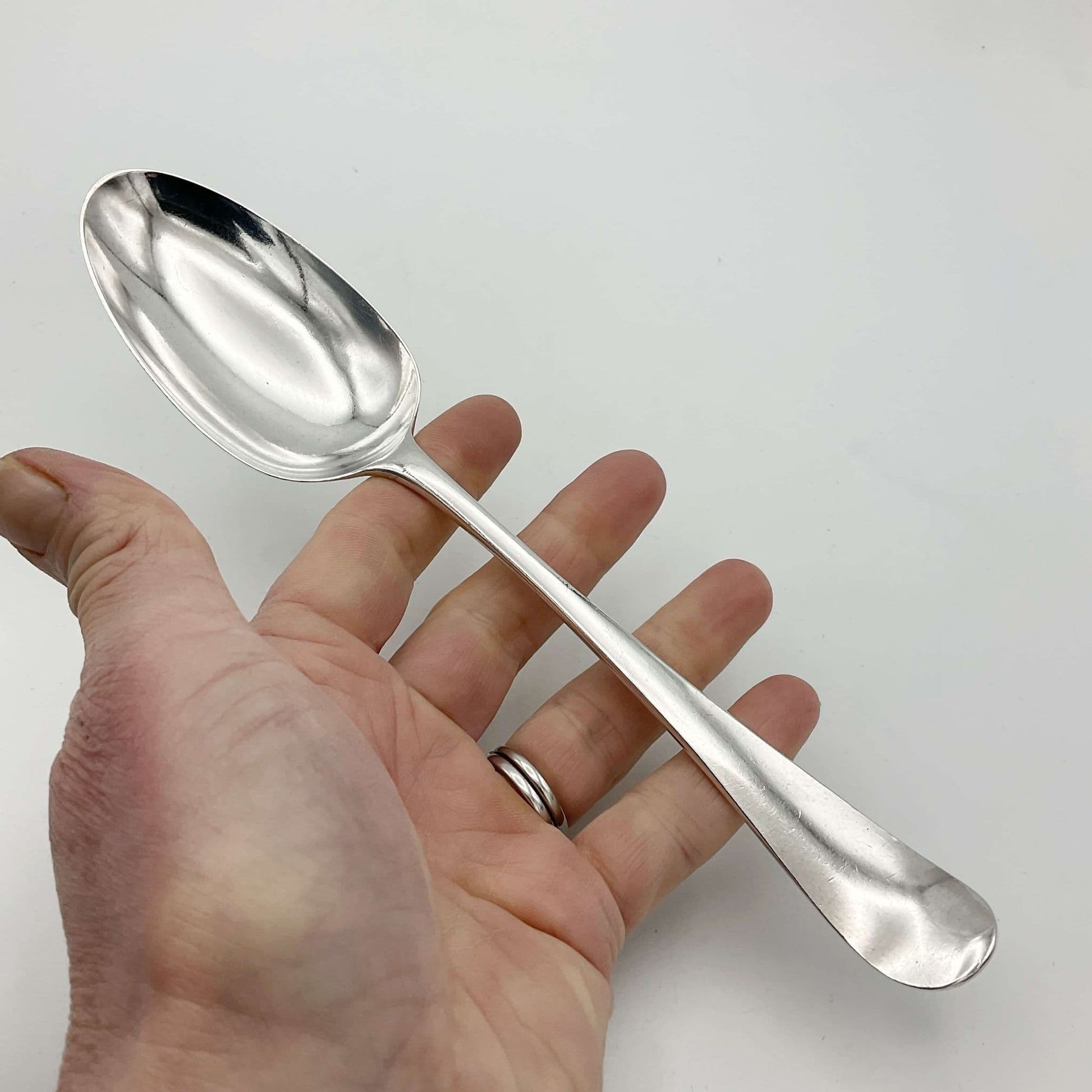 Antique silver serving spoon held in a hand