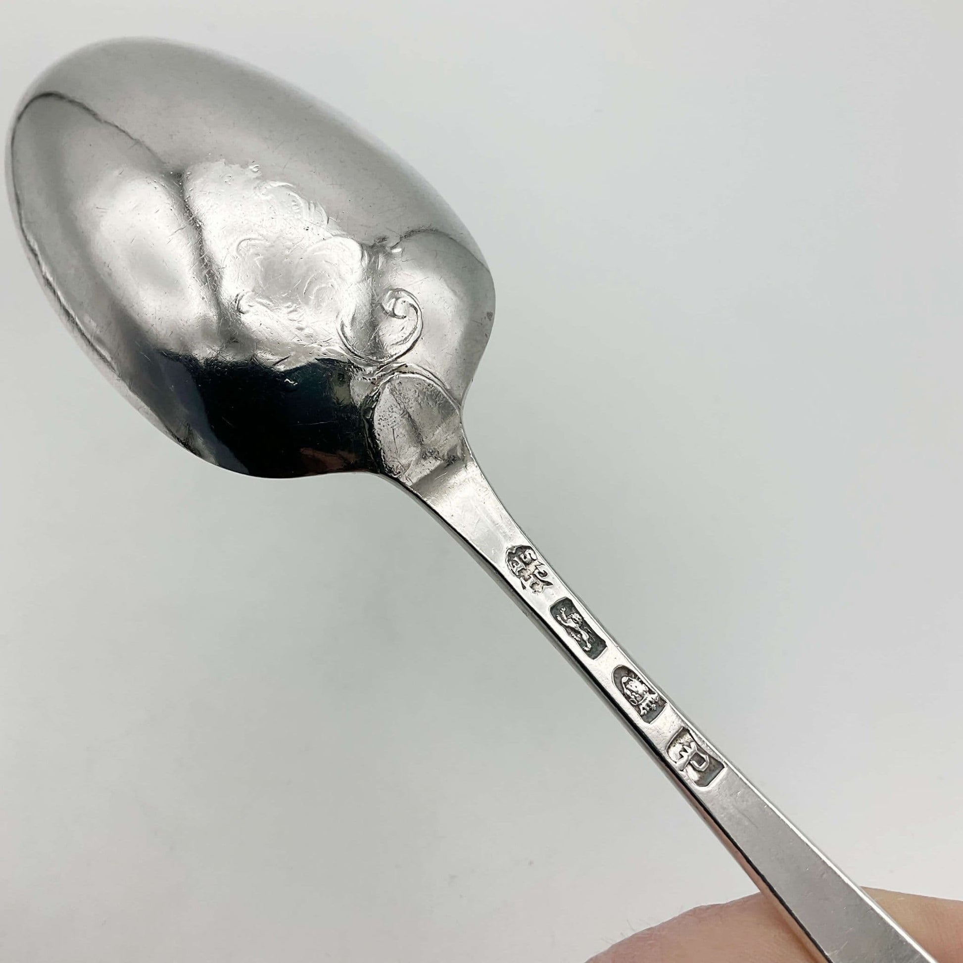 Antique silver serving spoon back view with scrolls on back of bowl and hallmarks