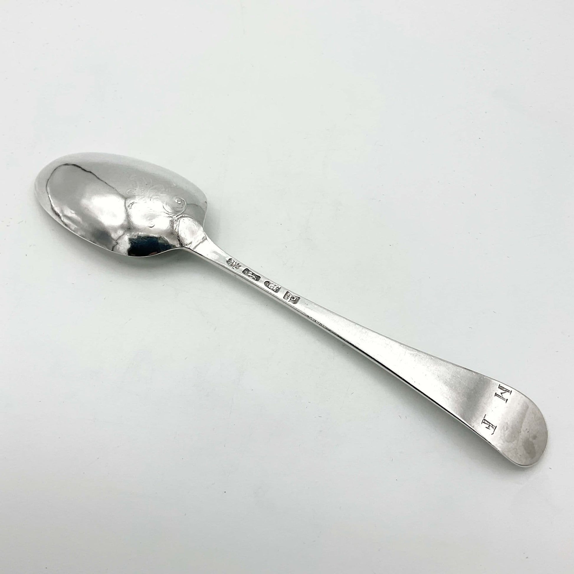 back view of antique silver serving spoon showing hallmarks, scroll design and MF at end of spoon