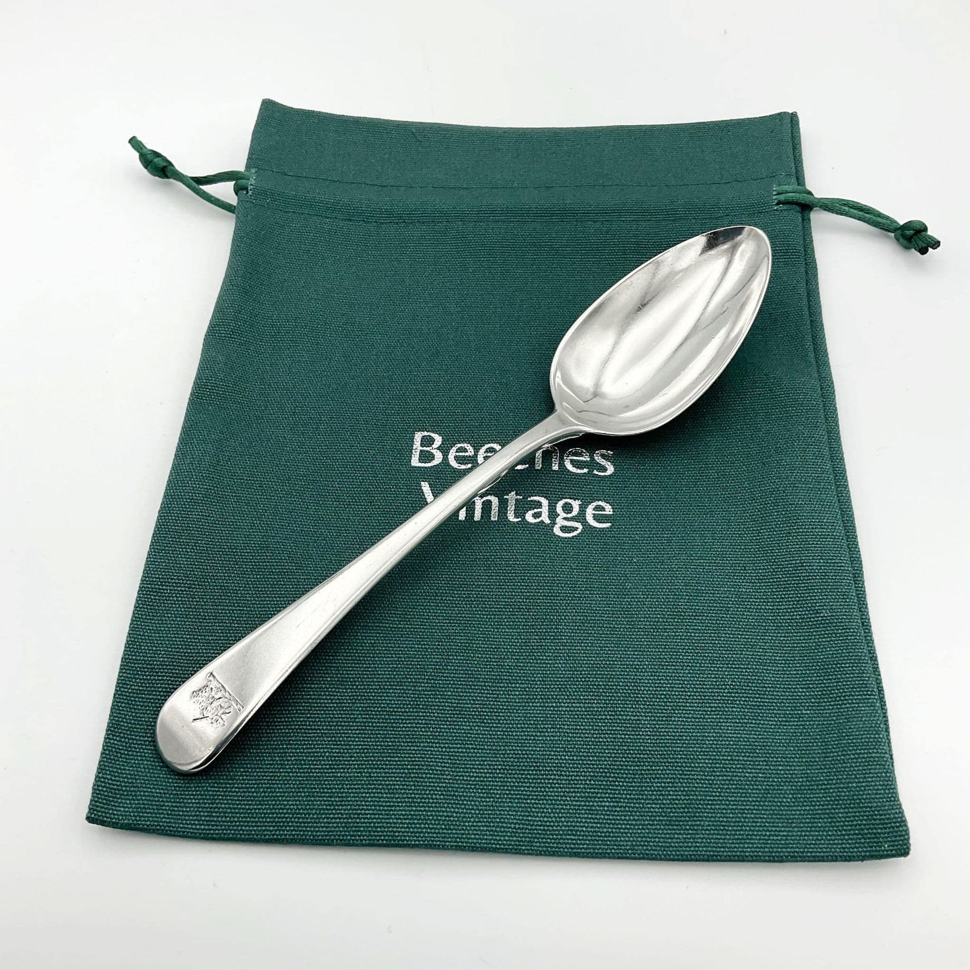 Antique Silver dessert spoon on a green cotton bag