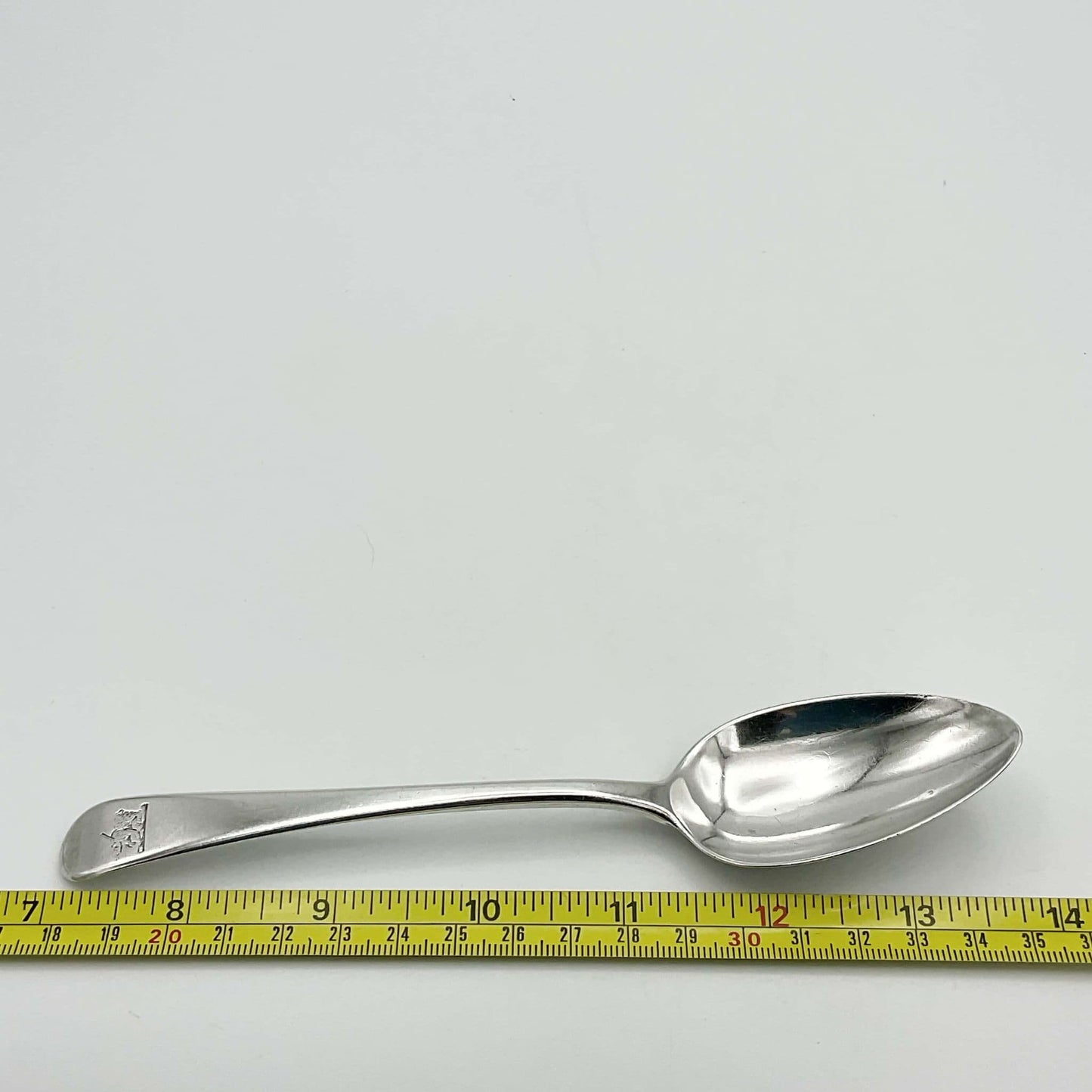 antique silver dessert spoon next to tape measure showing length as 17cm