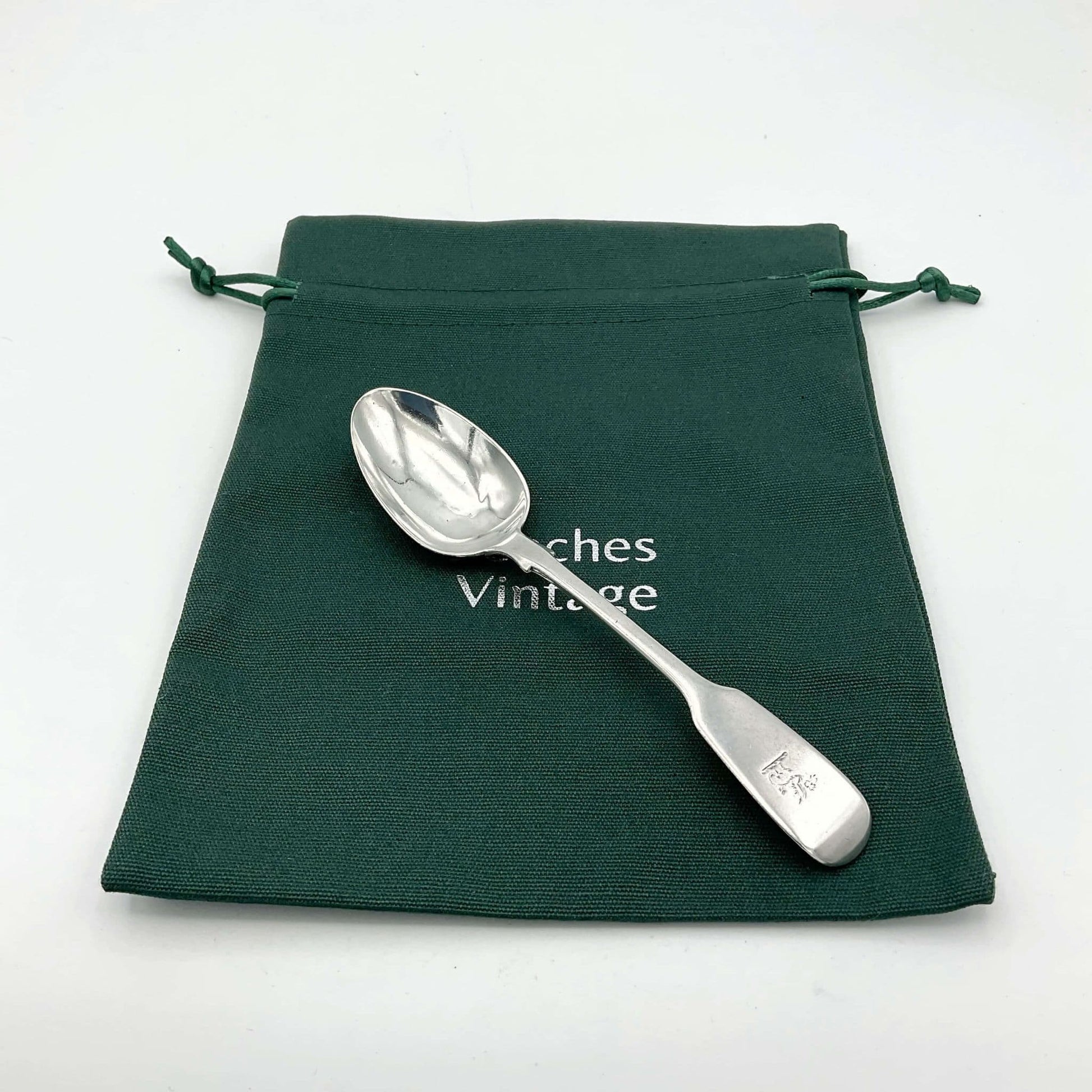 Antique silver teaspoon on a green cotton gift bag