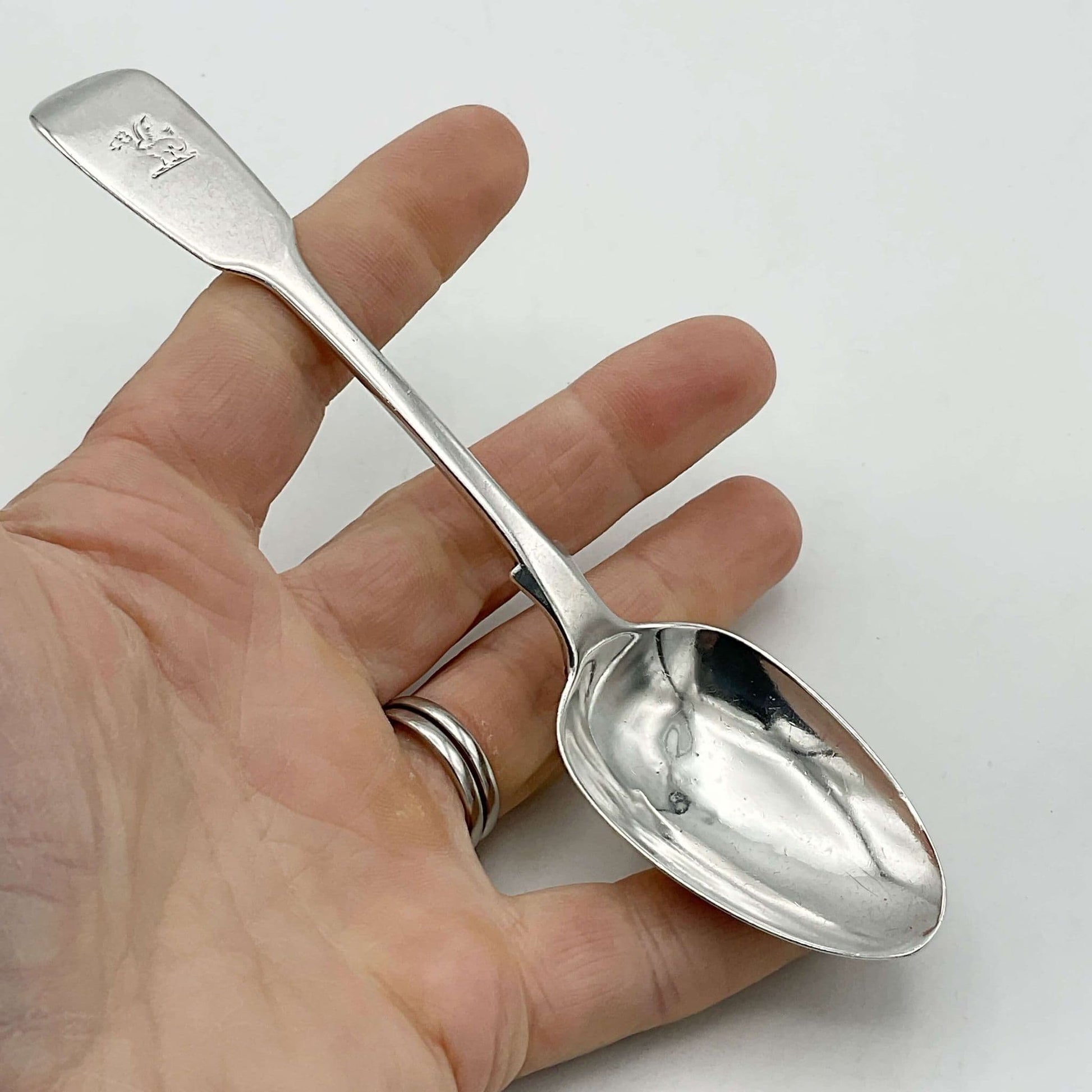 Antique silver teaspoon held in a hand