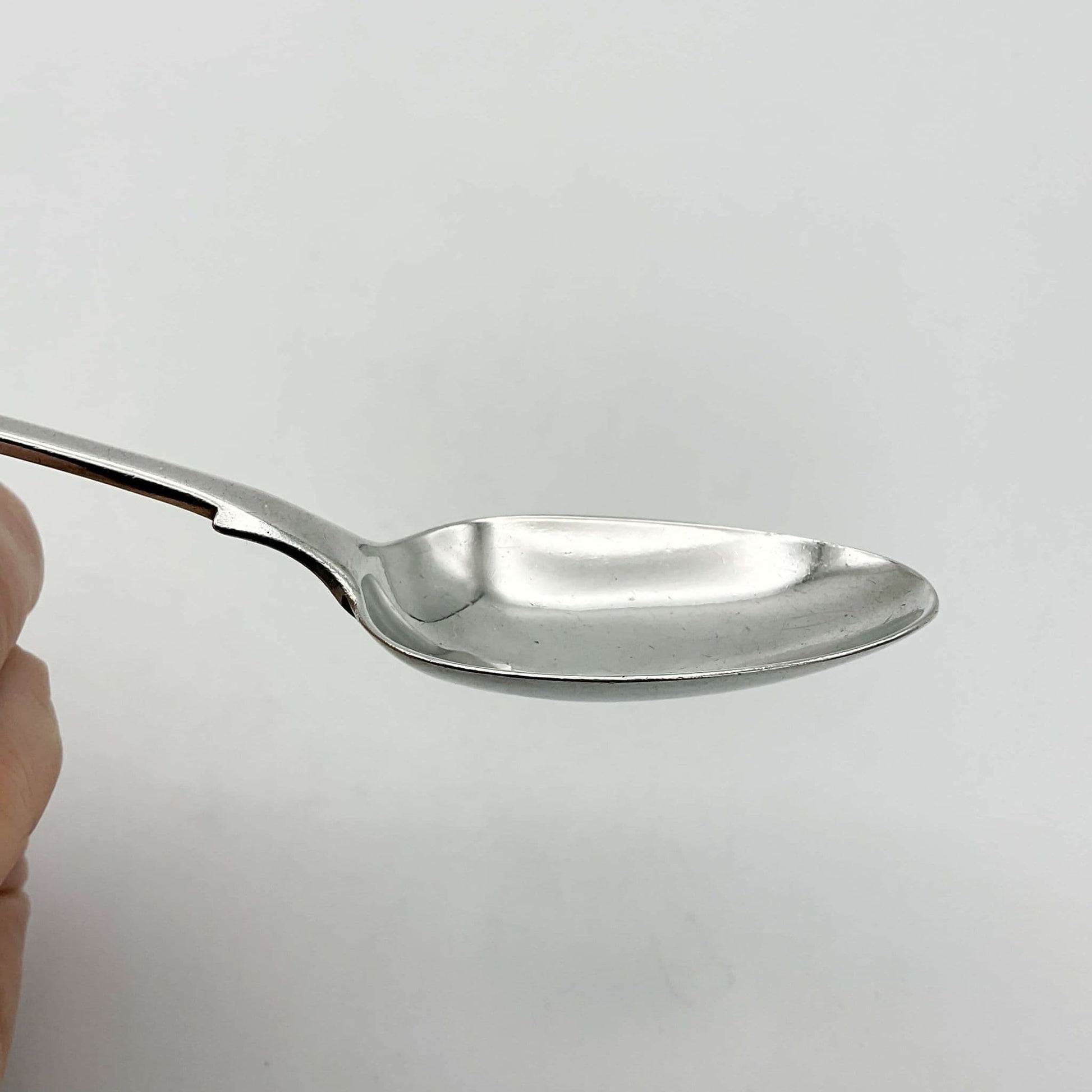 Bowl of an antique silver teaspoon with a white background