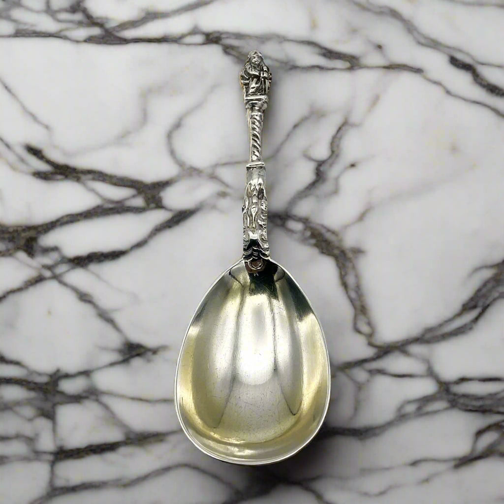 tea caddy spoon with gilded bowl and apostle handle on a marble surface
