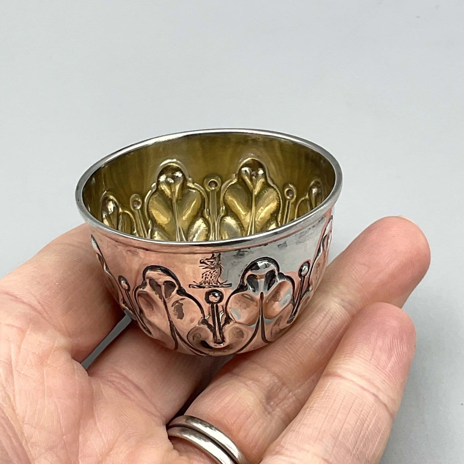 Antique Silver Salt pot with wavy design on outside and dragon motif and gilded interiorheld on hand