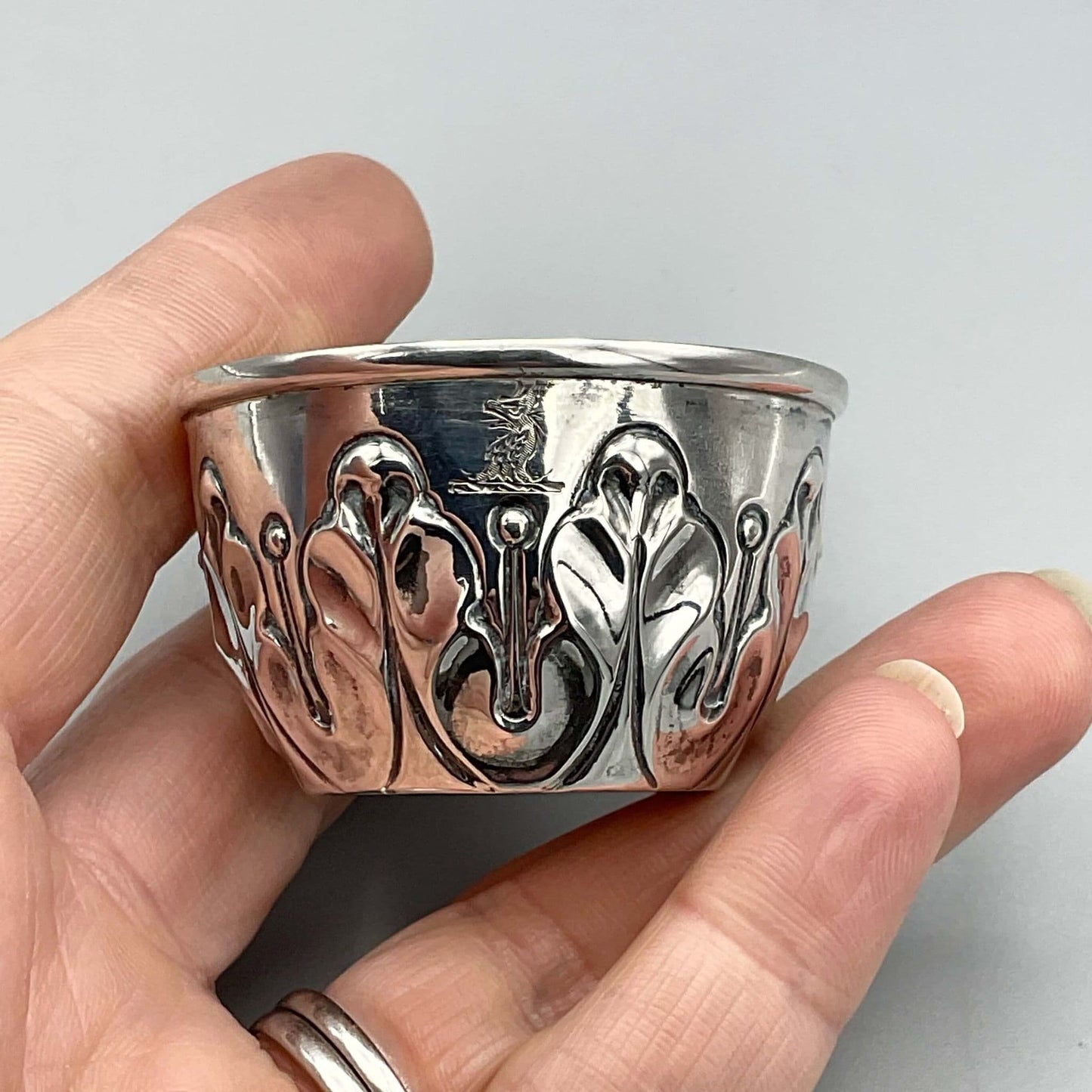 Antique Silver Salt pot with wavy design on outside with dragon motif held in fingers