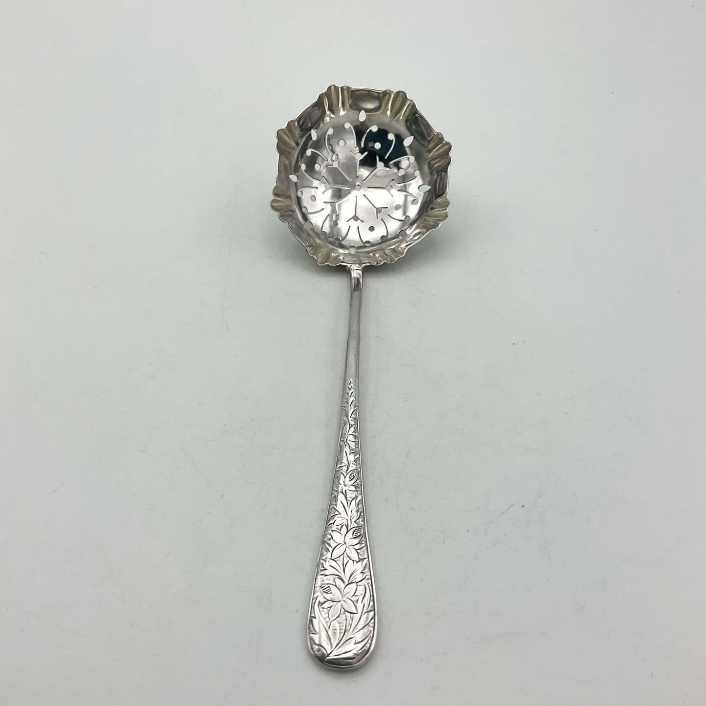 Antique Silver Sifter Spoon with flowers on the handle on white background And hexagonal bowl