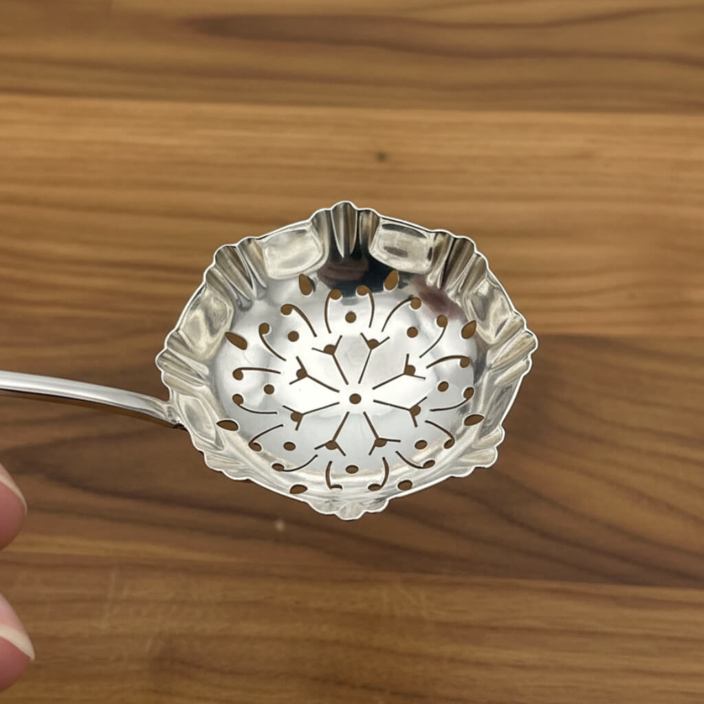 Silver sugar sifter spoon on a wooden surface