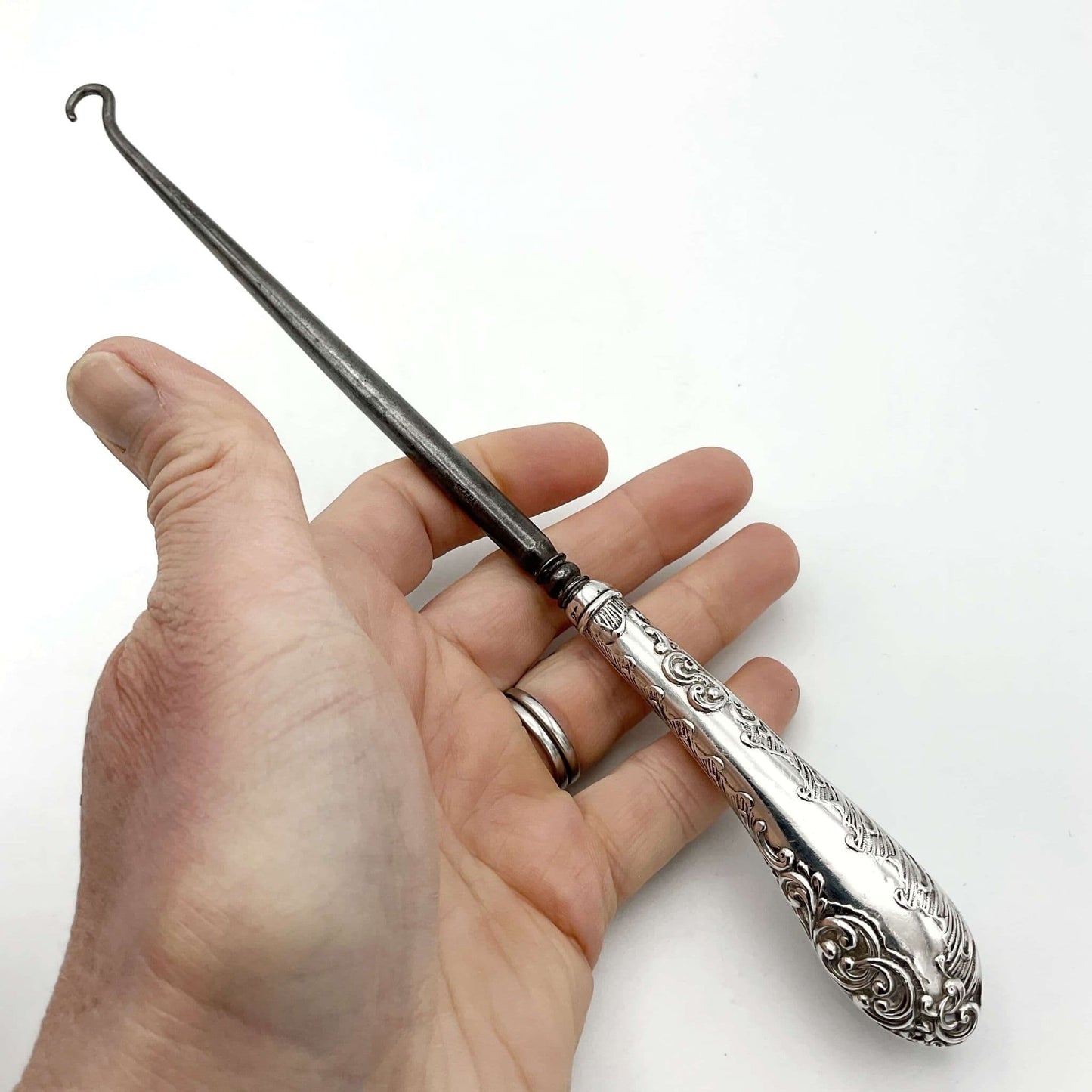 silver handled antique button hook being held in a hand