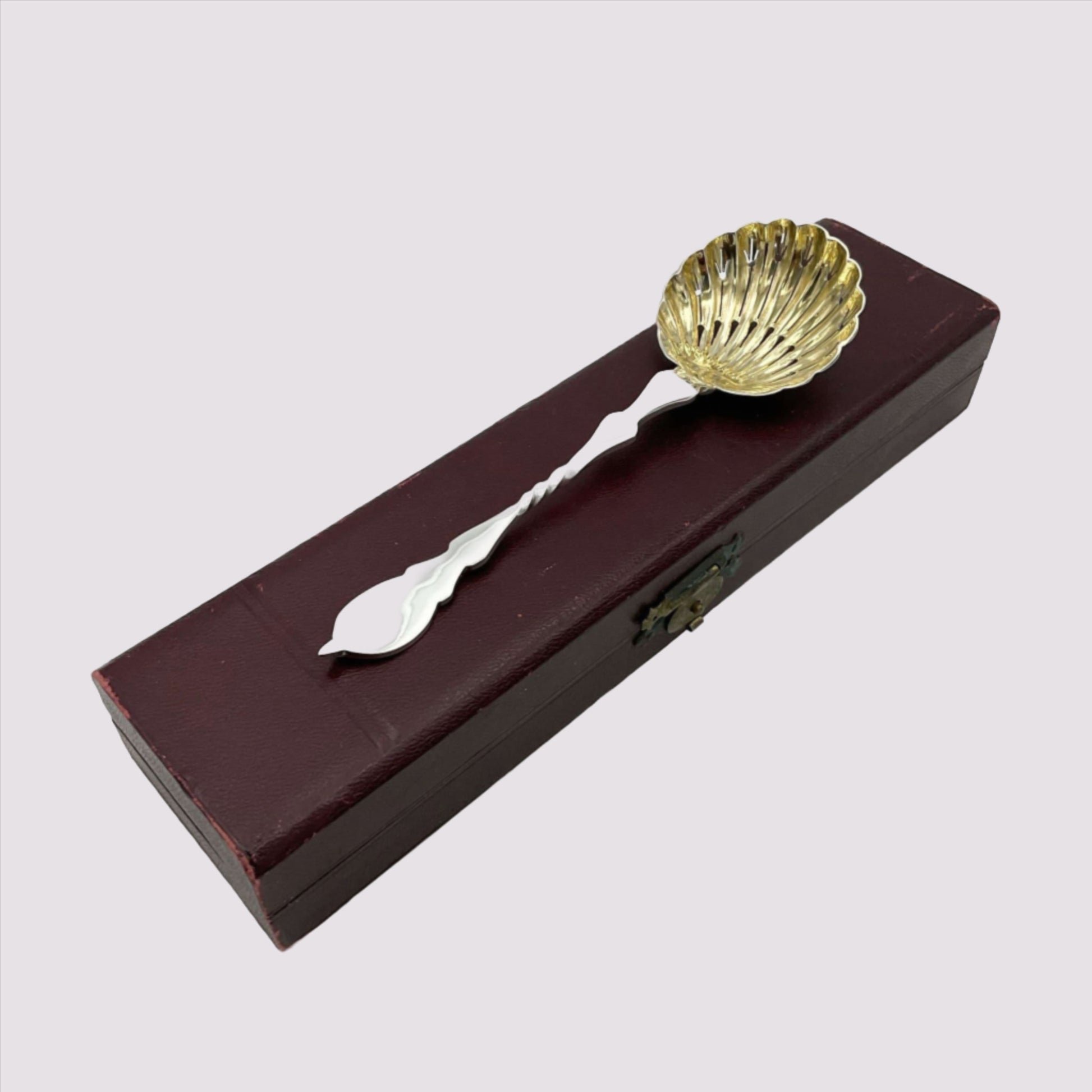 Beautiful gilded Silver sugar sifter spoon on top of presentation box