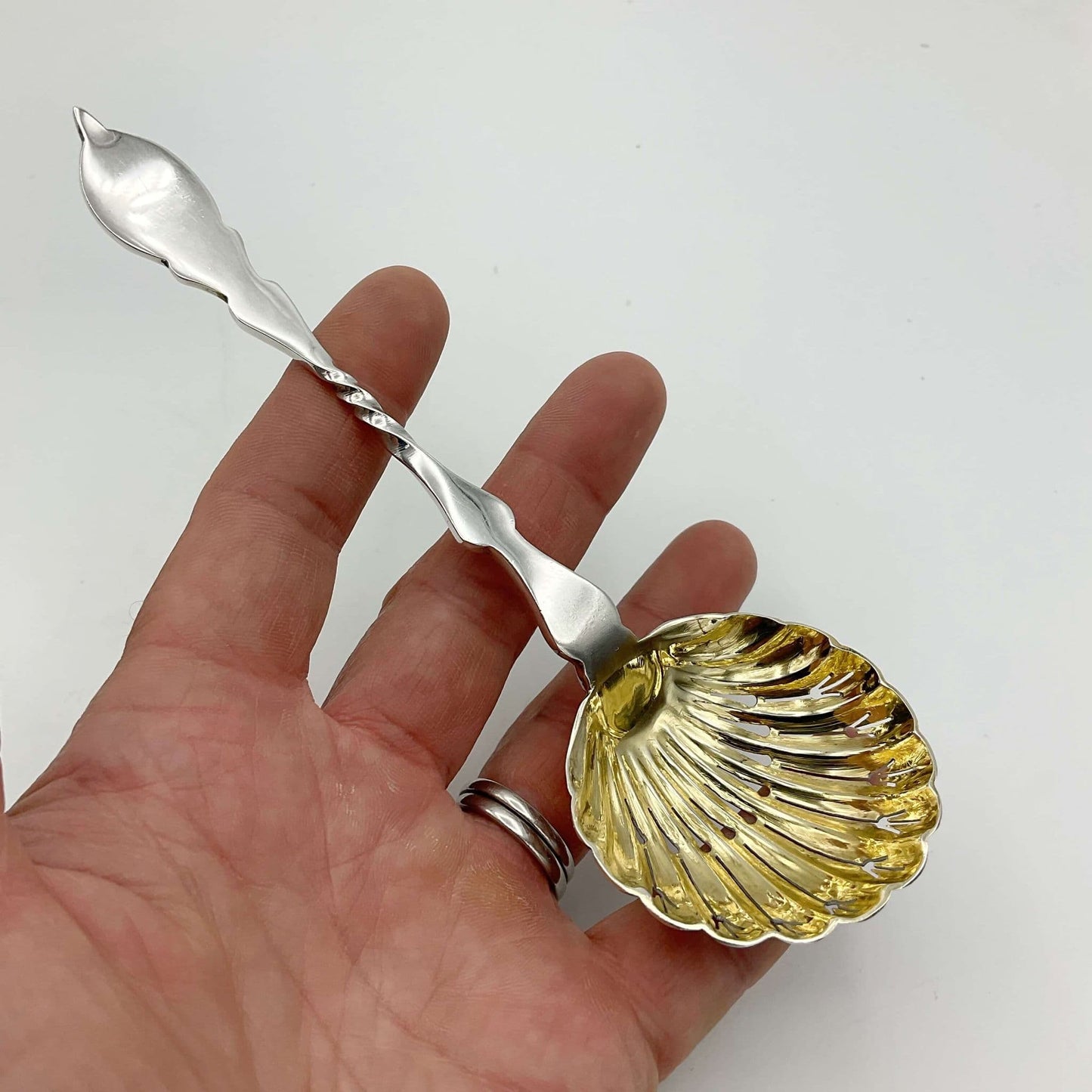 Beautiful gilded Silver sugar sifter spoon held in a hand