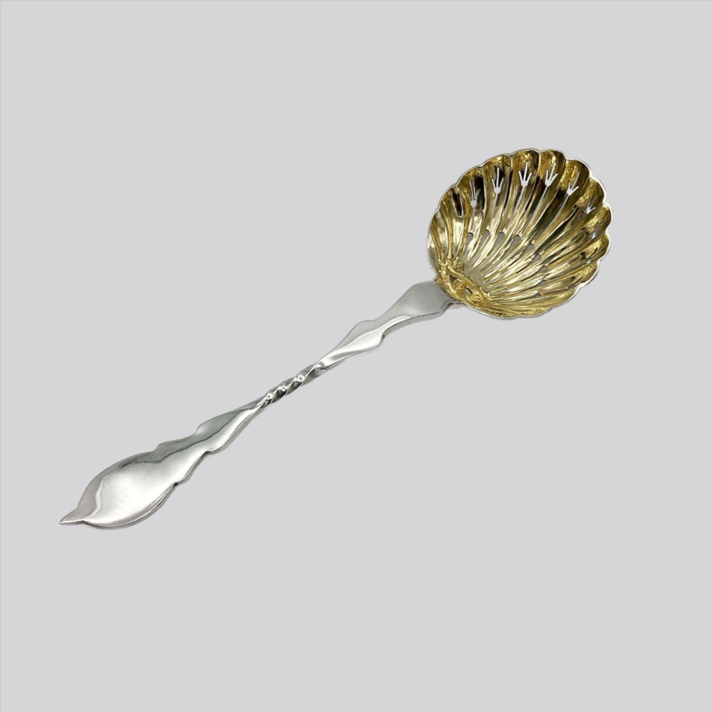 Beautiful gilded Silver sugar sifter spoon on a plain white background