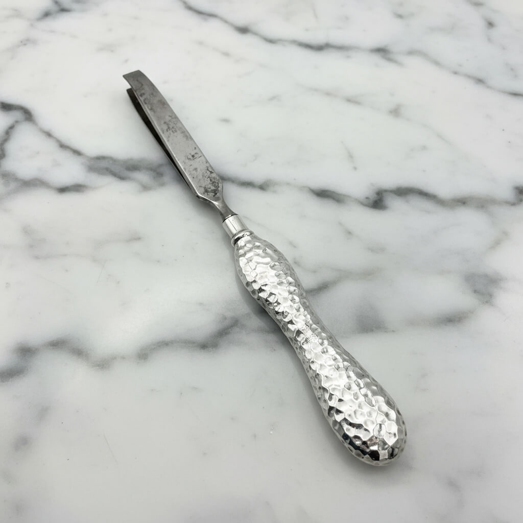 Silver tweezers with a textured handle on a marble surface