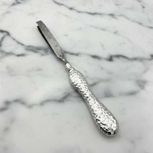 Silver tweezers with a textured handle on a marble surface