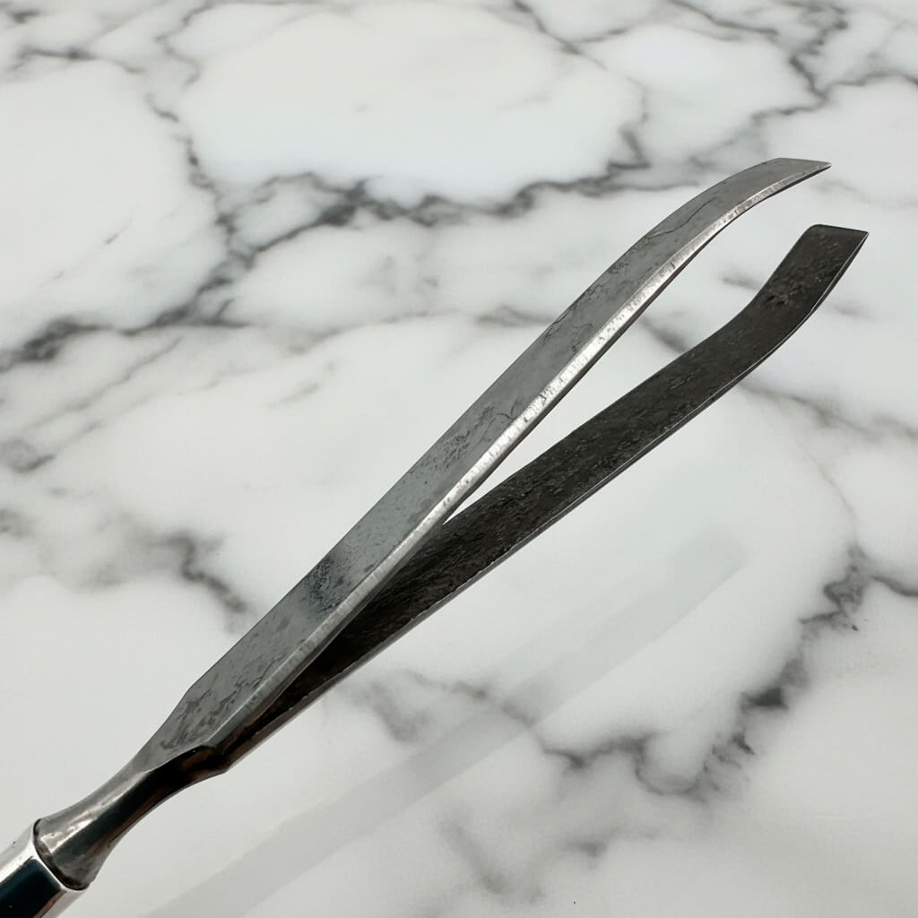 Metal tweezers on a marble surface