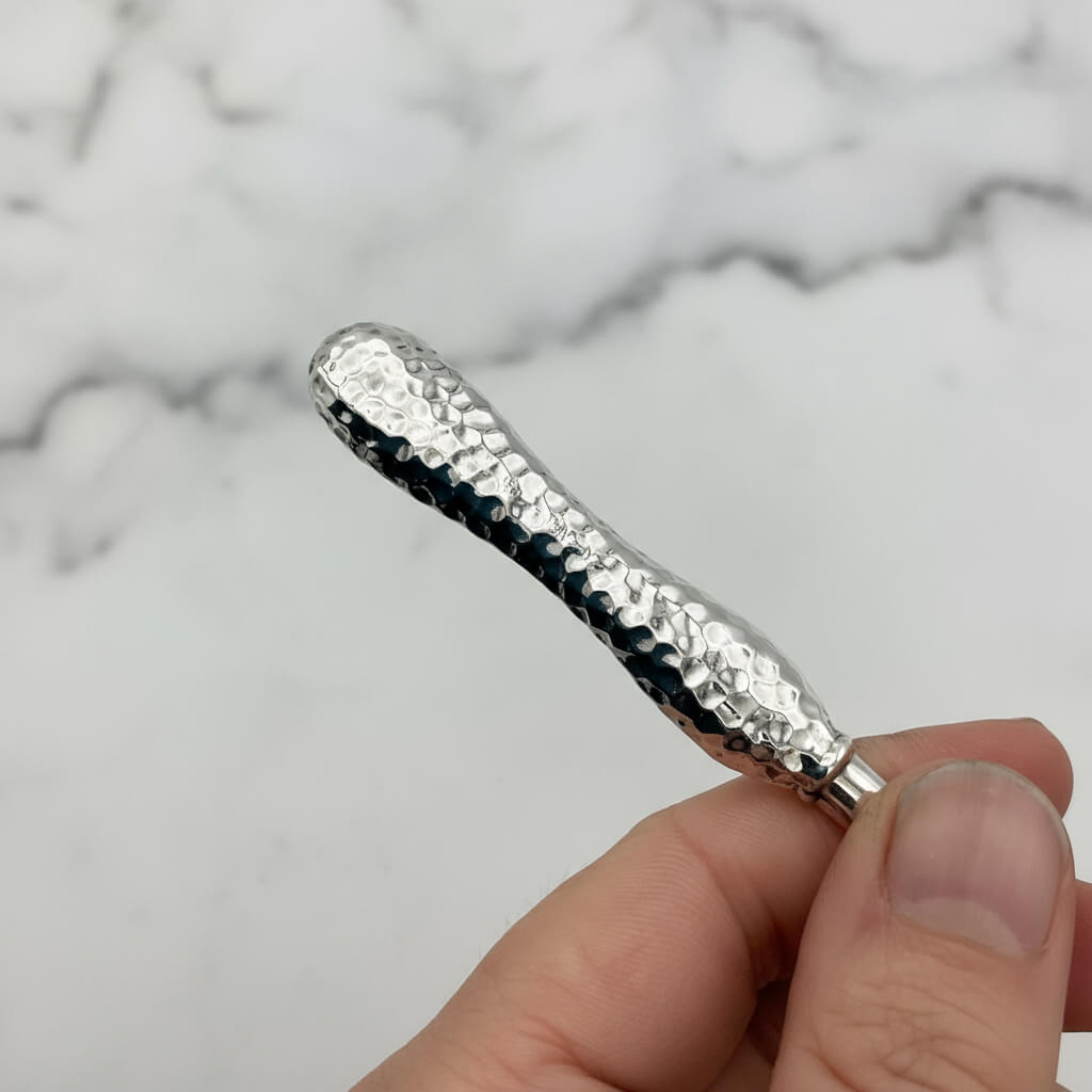 Silver tweezers held in a hand against a marble background