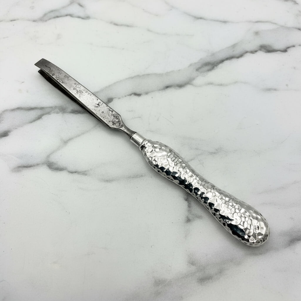 Silver tweezers with textured handle on a marble background