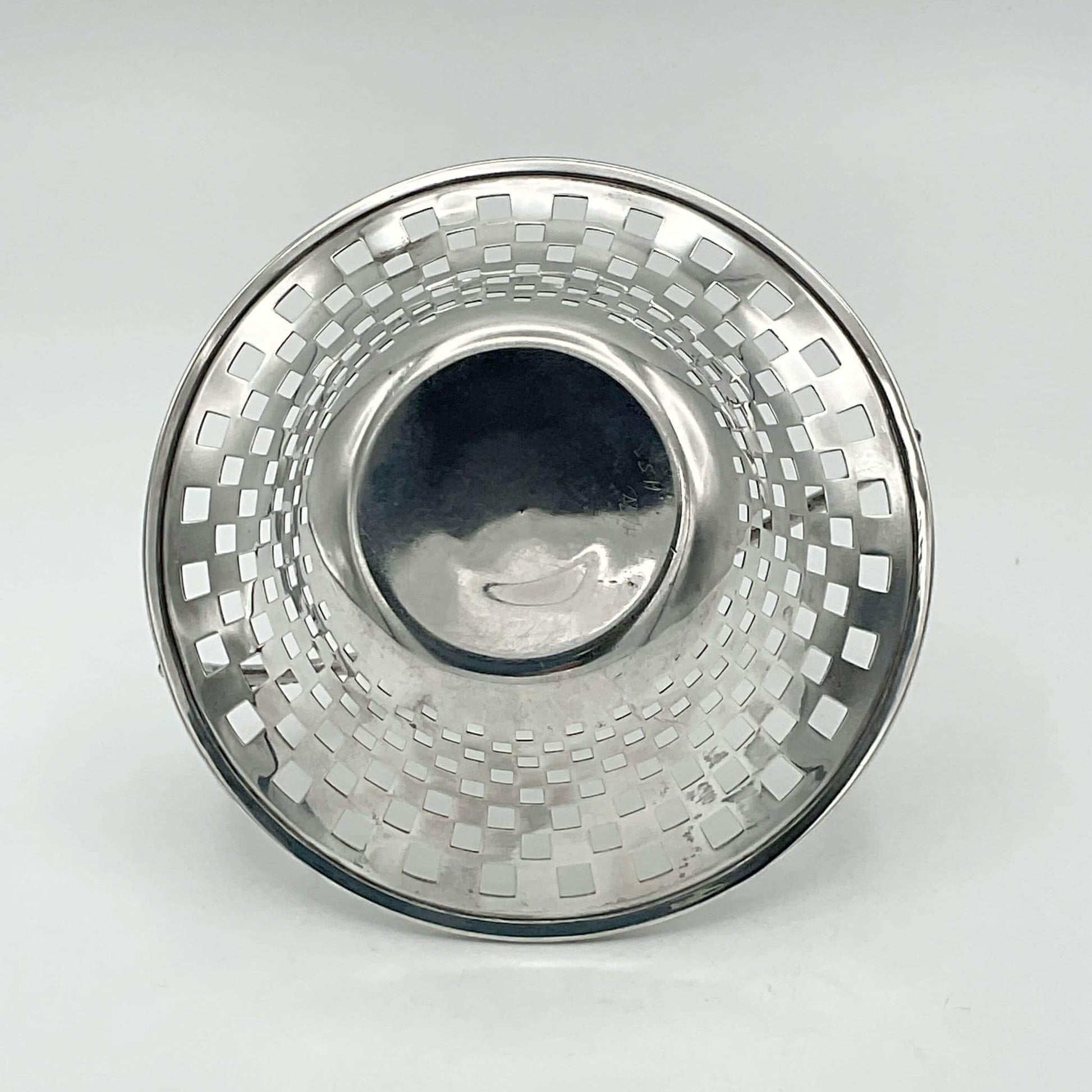 base of silver basket with a textured design on a light gray background