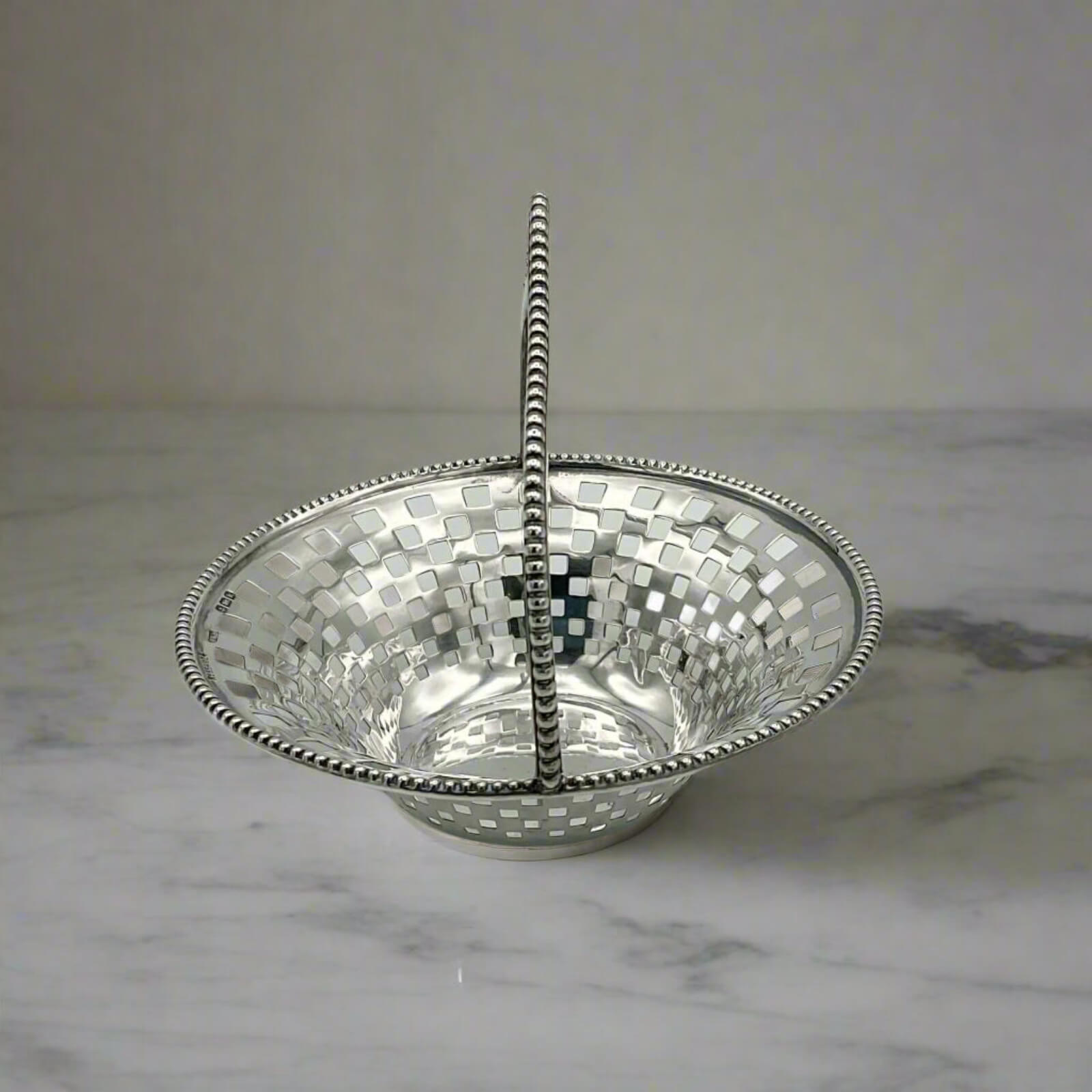 Silver basket on a marble surface with a neutral background
