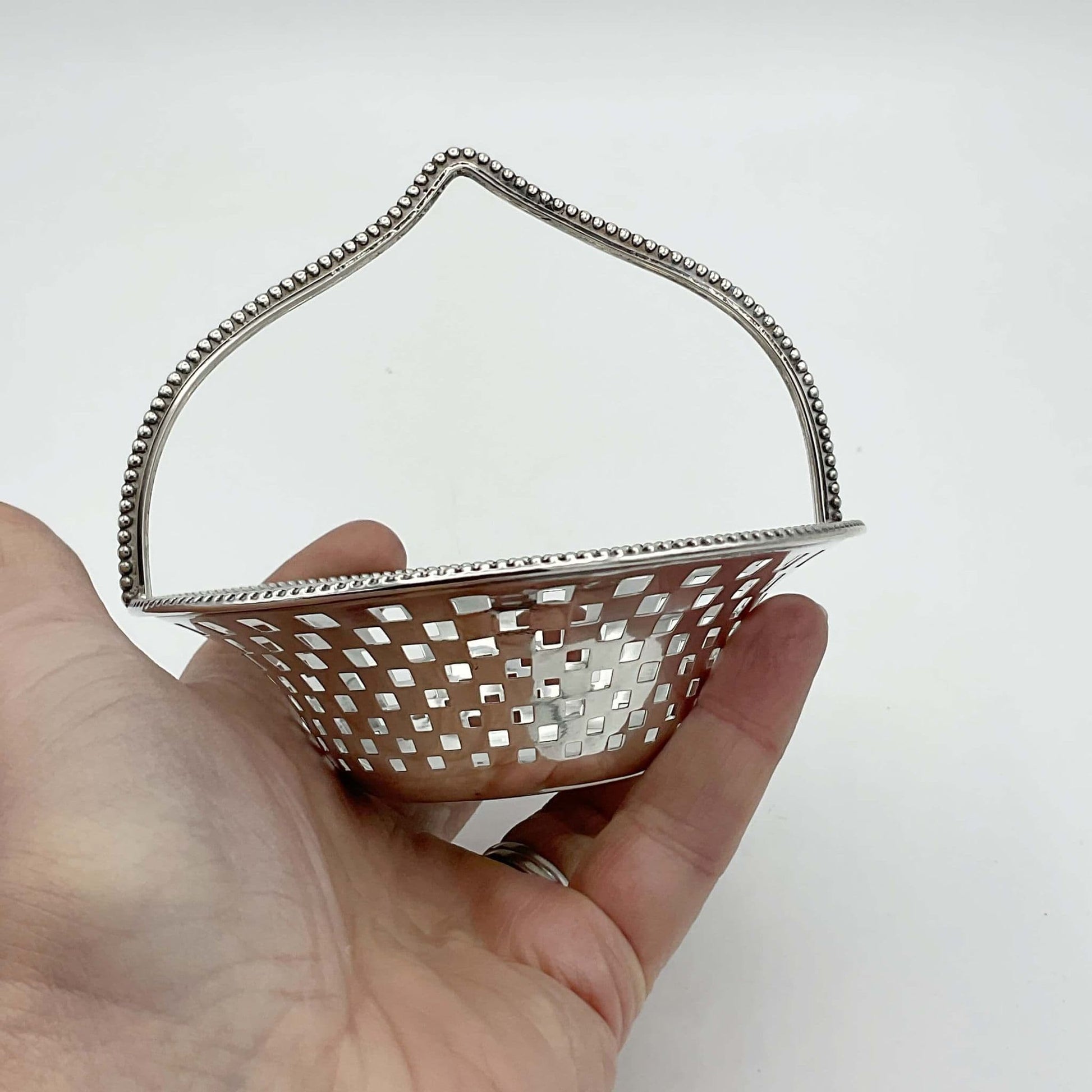 Antique Silver Basket with handle on white background held in a hand