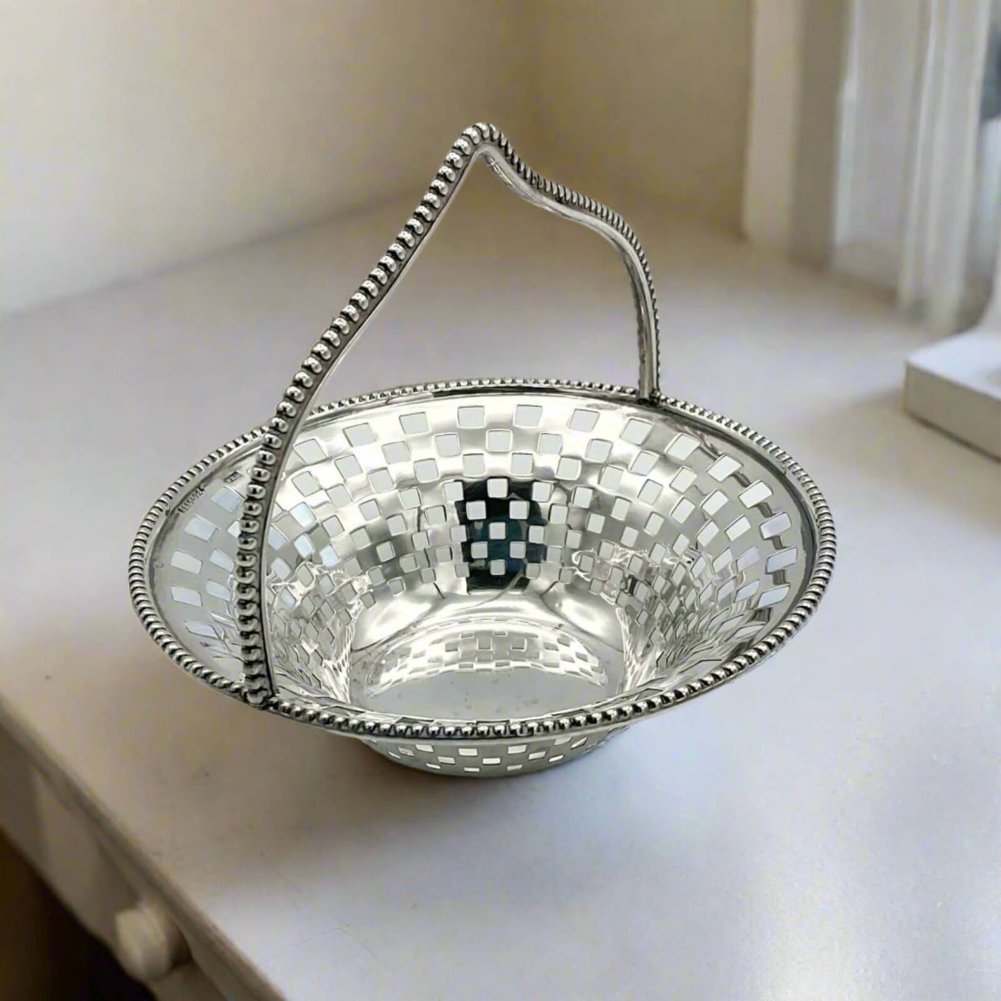 Decorative silver basket with a checkered pattern on a light surface
