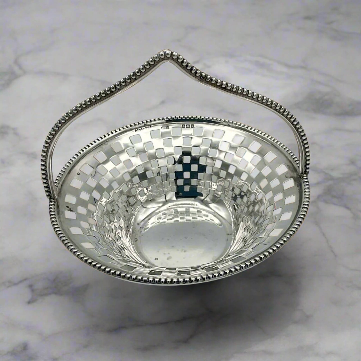 Silver bowl with a checkered pattern on a marble surface