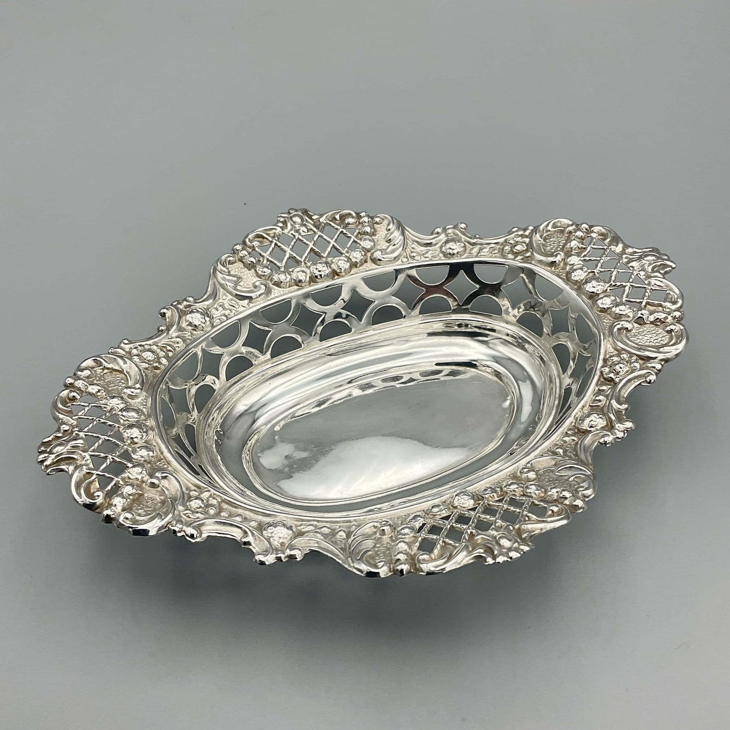 Ornate silver pierced bowl on grey background 