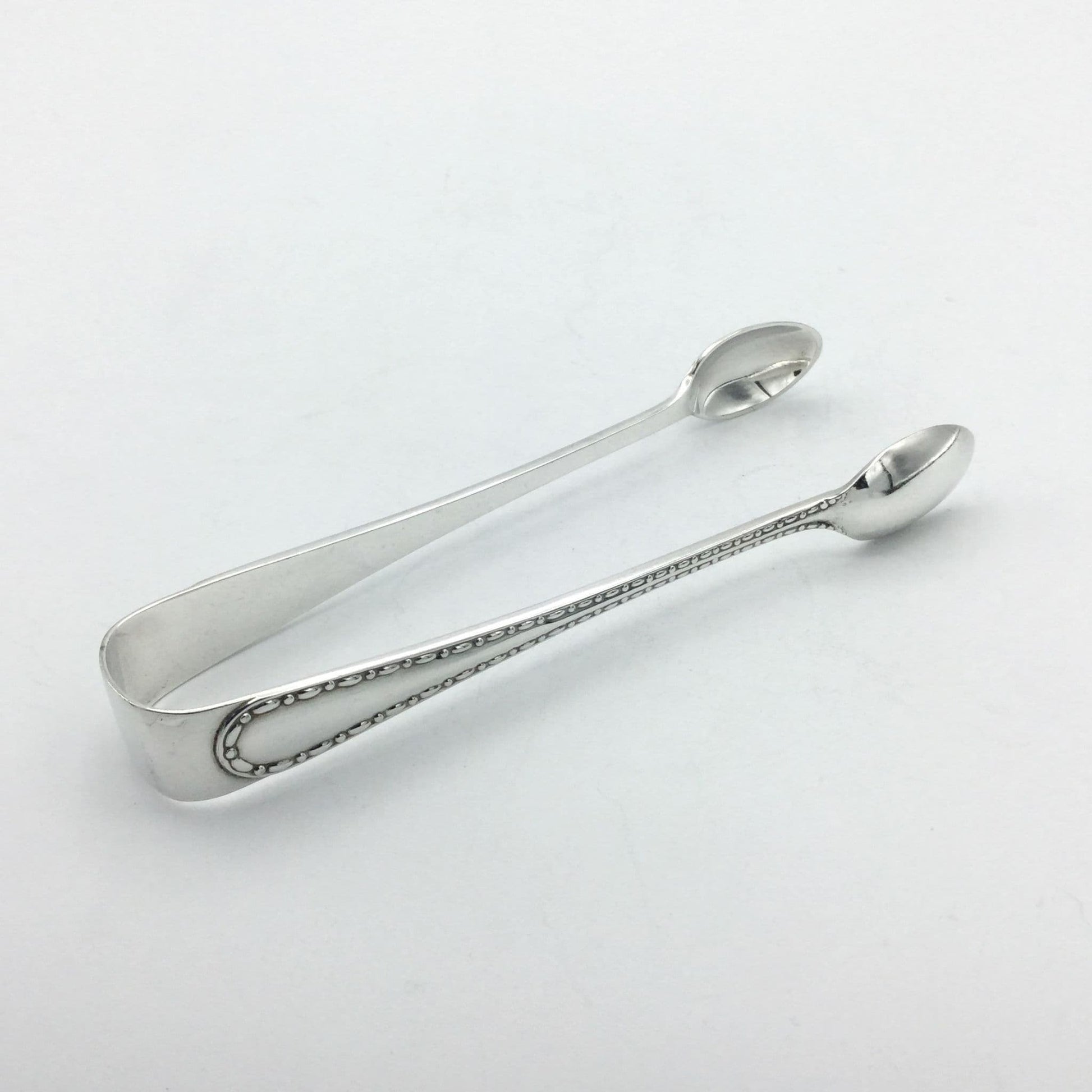 silvere sugar tongs pointing away from camera showing pattern on arm