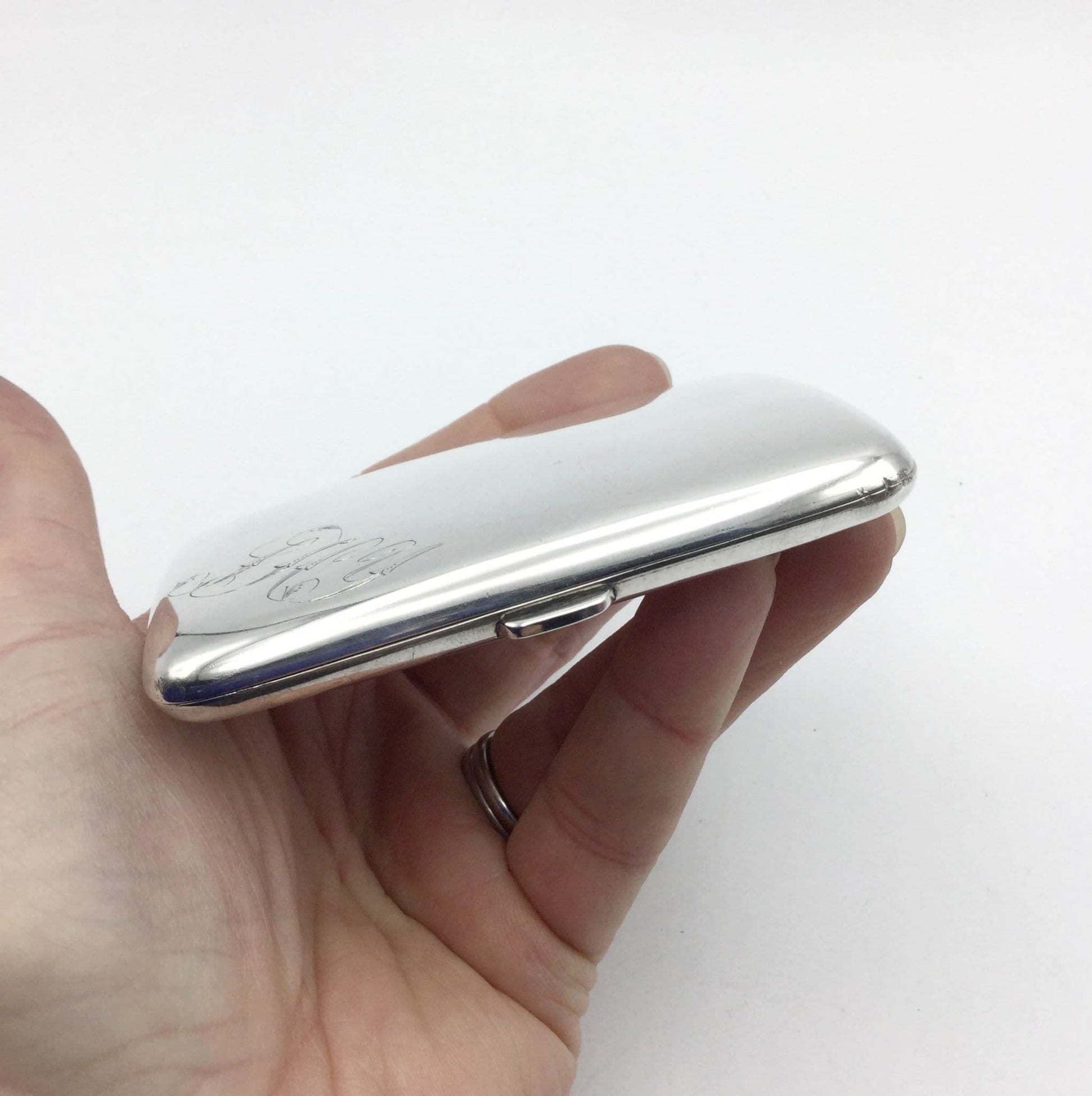 side view of antique silver cigarette case showing the clasp and held in a hand