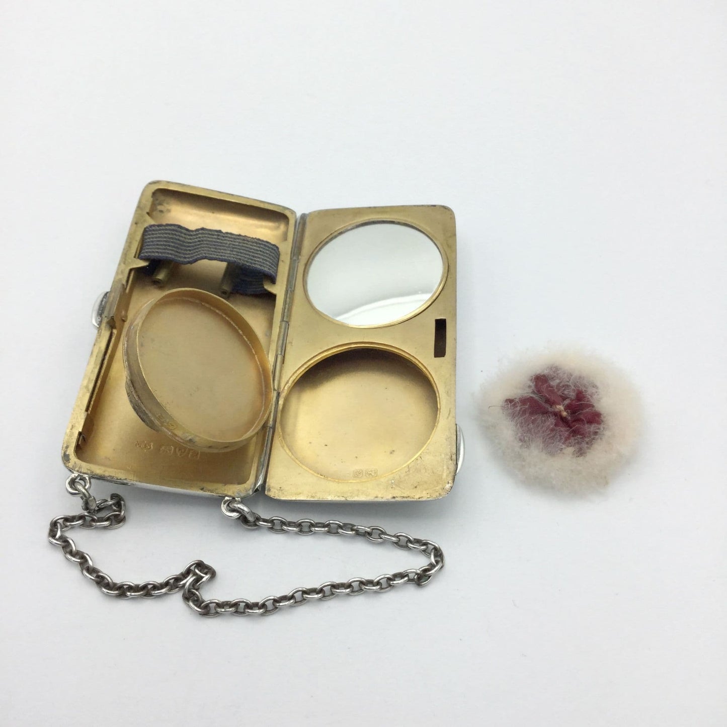 gilded golden inside of case showing a mirror, powder area and chain, with the powder puff at the side