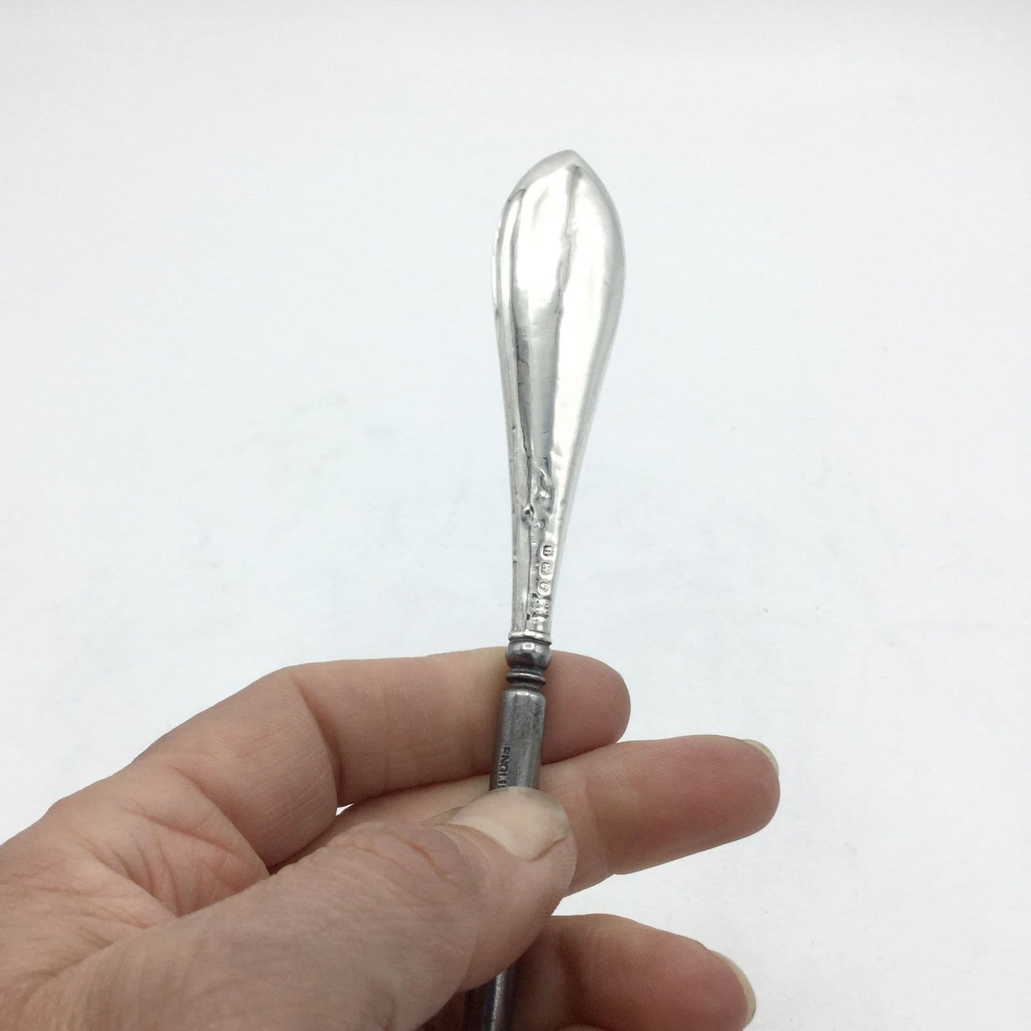 Silver handled antique button hook with a shiny handle held upright