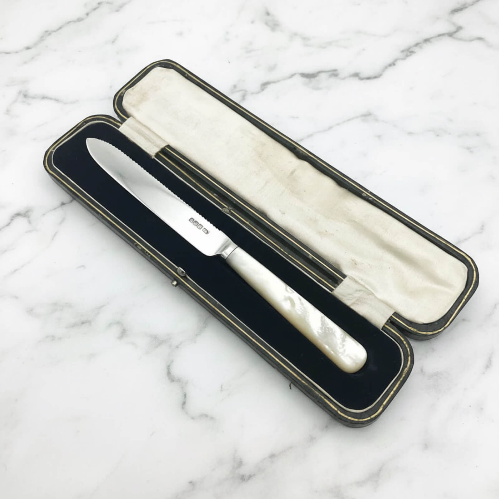 Knife with a decorative handle in an open case on a marble surface