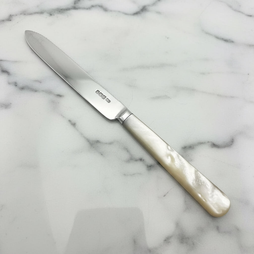 silver knife with mother of pearl handle on a marble worktop