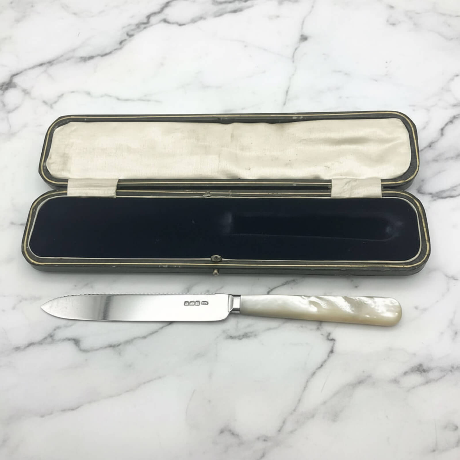 Knife with a decorative handle in an open case on a marble surface