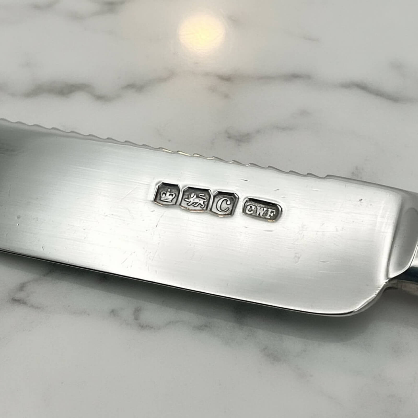Silver knife with engraved hallmarks on a marble surface