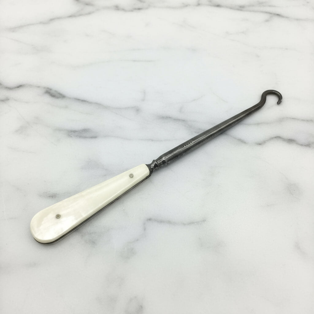 Antique bone handled button hook on a white background