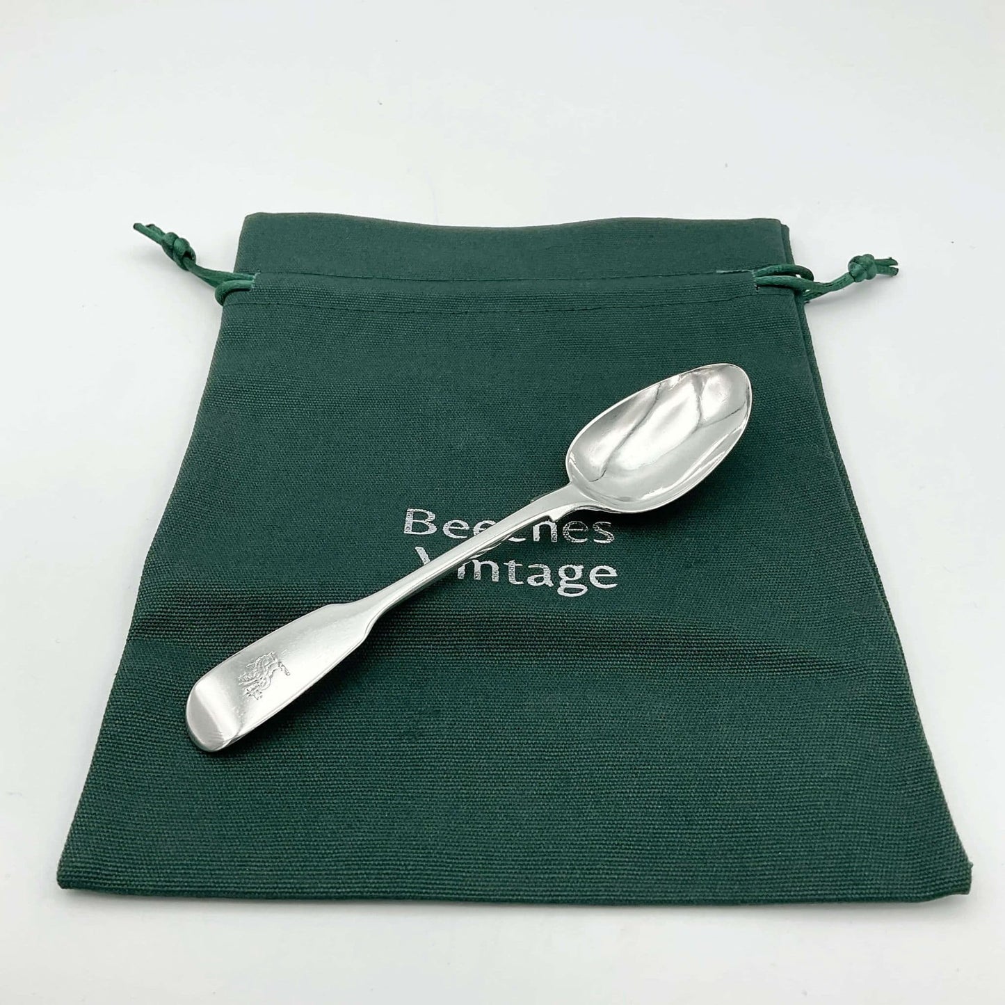 Antique silver teaspoon on a green cotton gift bag