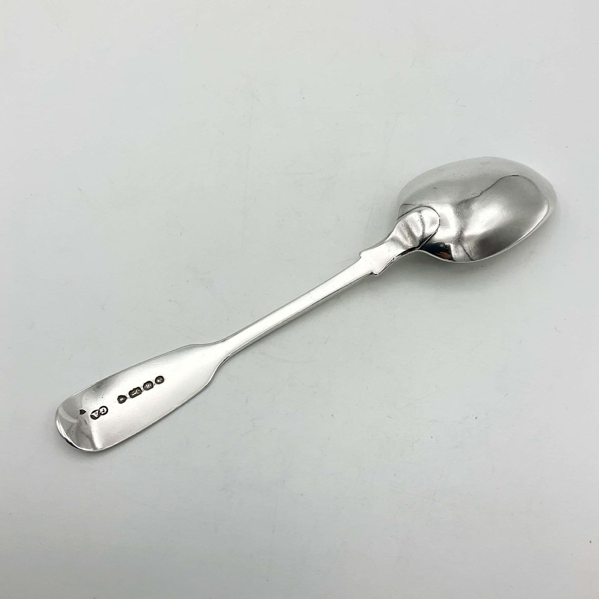 Back view of an antique silver teaspoon on a white background